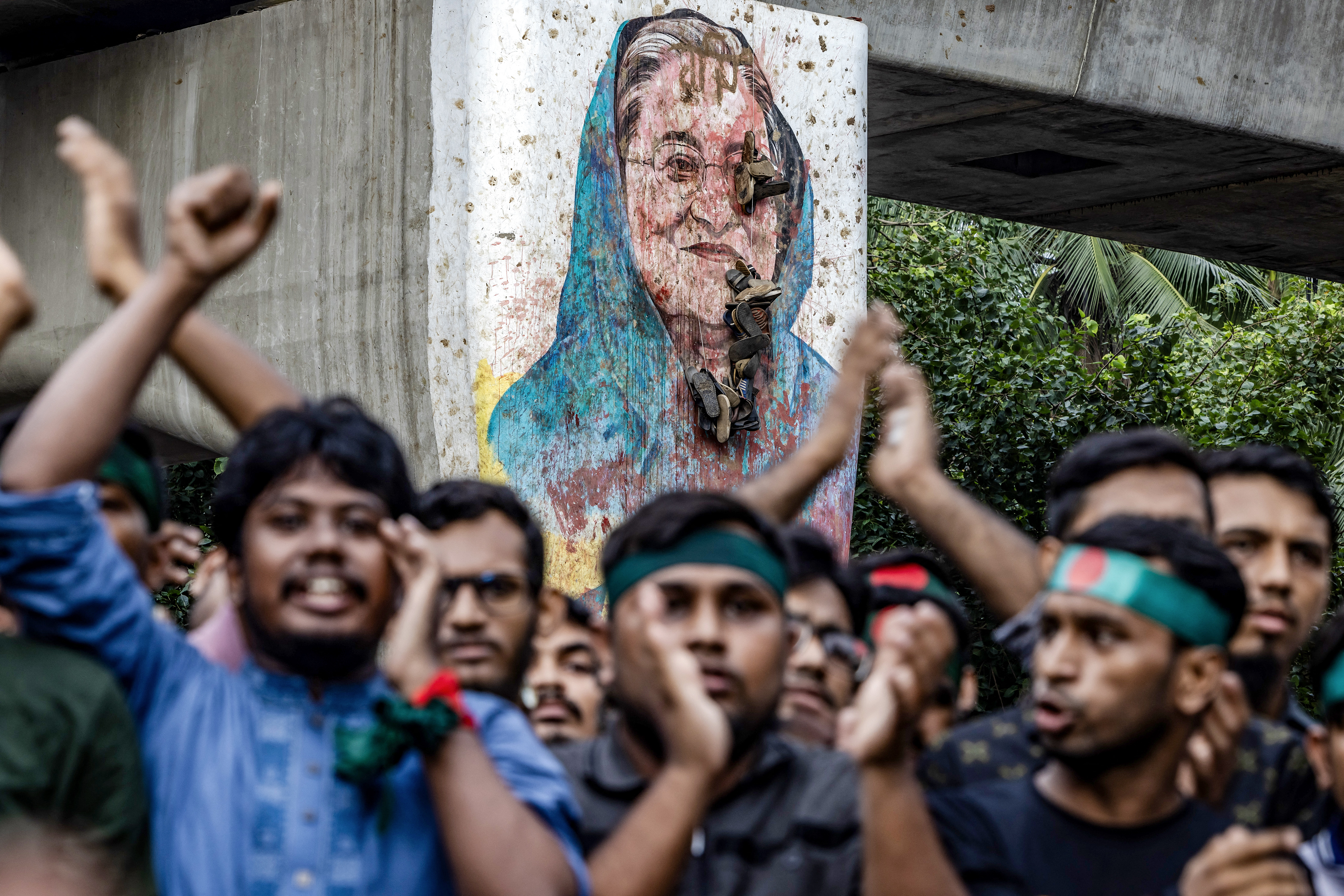 (FILES) Students chant slogans near a vandalised mural of Bangladesh's ousted Prime Minister Sheikh Hasina, during a protest demanding accountability and trial against Hasina, near Dhaka University in the capital on August 12, 2024.