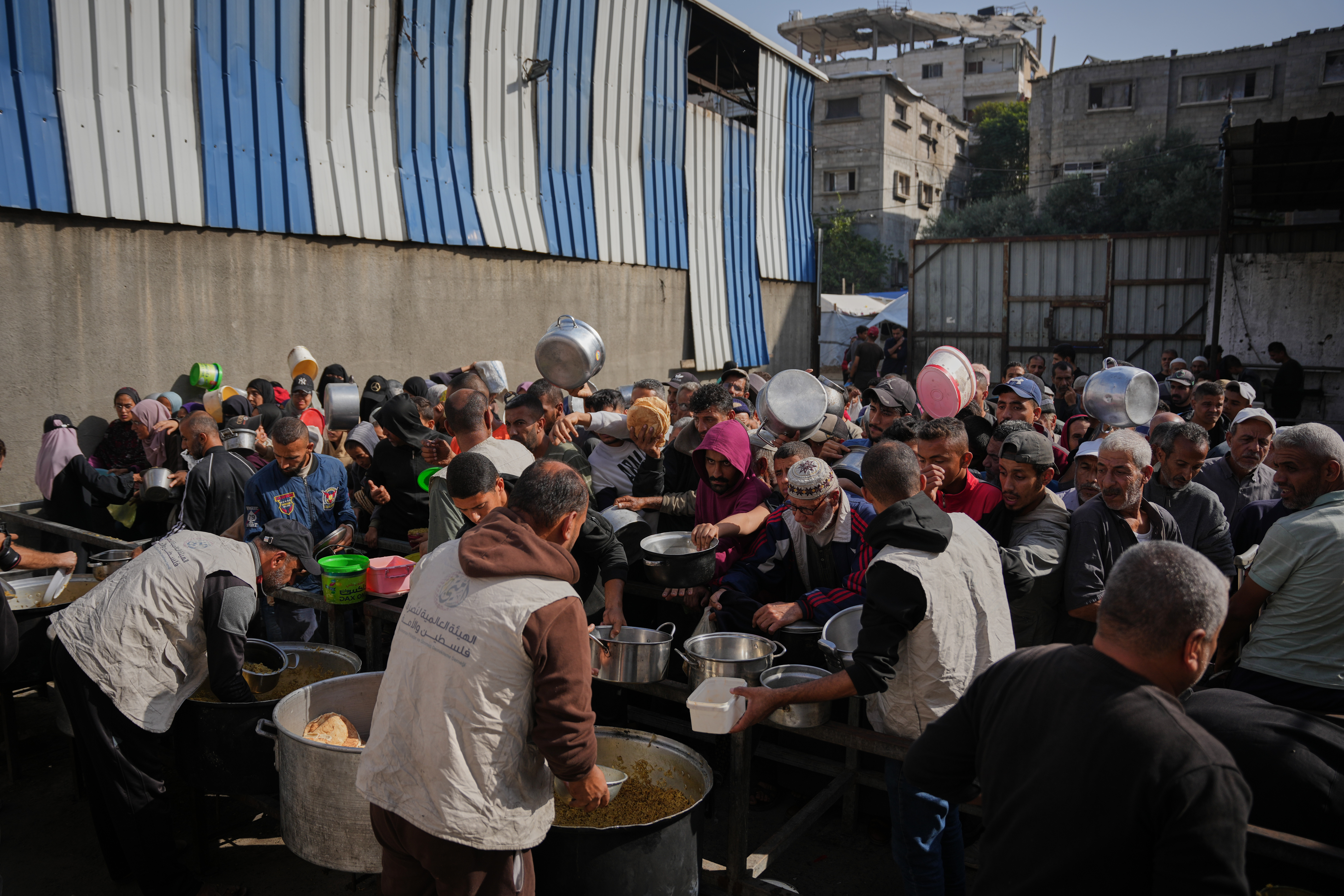 Palestinians struggle to receive donated food at a community kitchen in Nuseirat, central Gaza Strip, Wednesday, Nov. 19, 2025. (AP Photo/Abdel Kareem Hana)