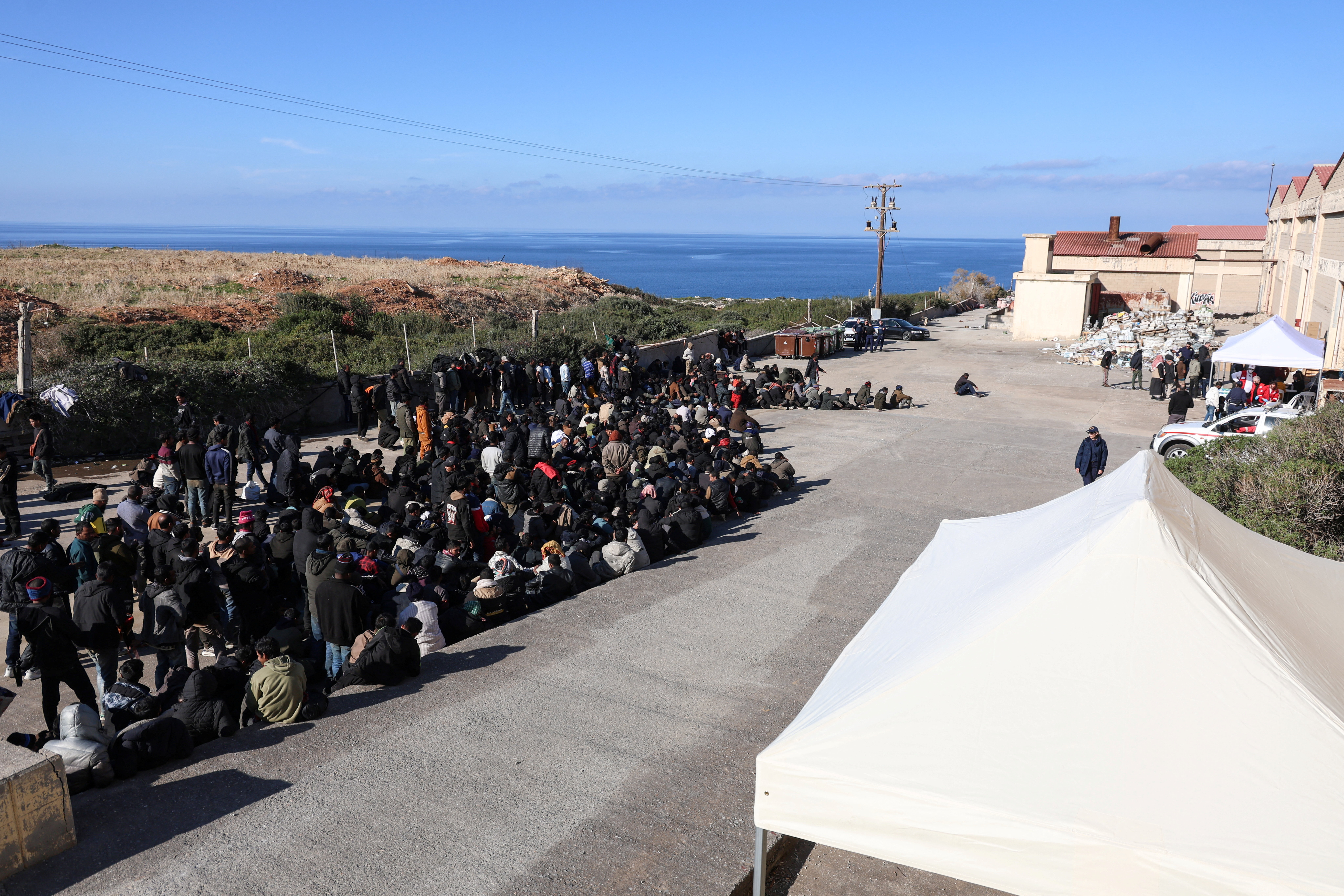 Asylum seekers sit outside their temporary shelter in the town of Rethymno, on the island of Crete, Greece
