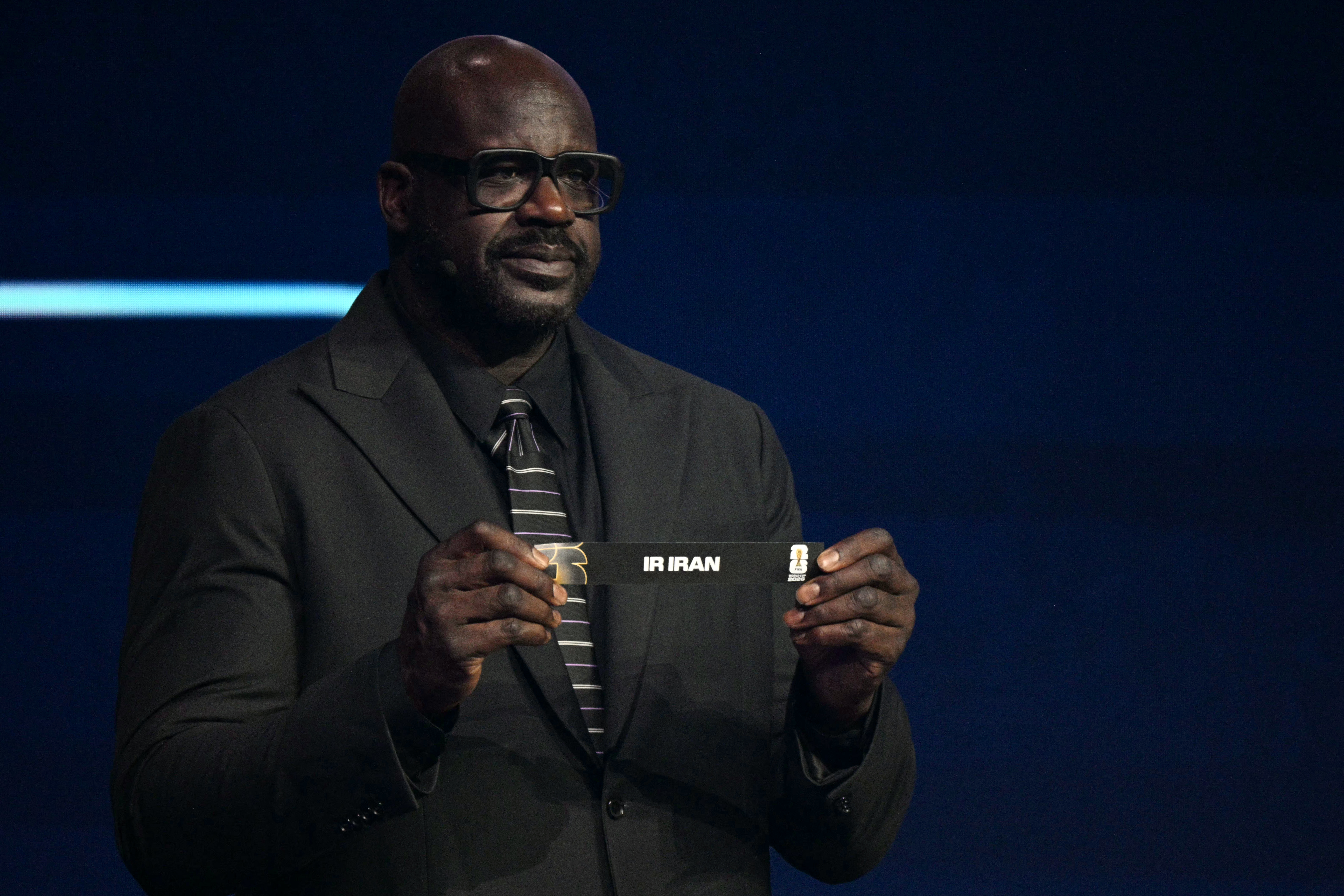 US draw assistant and former NBA player Shaquille O’Neal shows the card reading Iran during the draw for the 2026 FIFA World Cup, at the Kennedy Center, in Washington, DC, on December 5, 2025