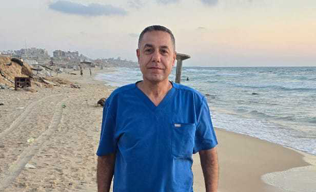 Doctor on a break, looking exhausted but good-natured in his scrubs standing on the beach