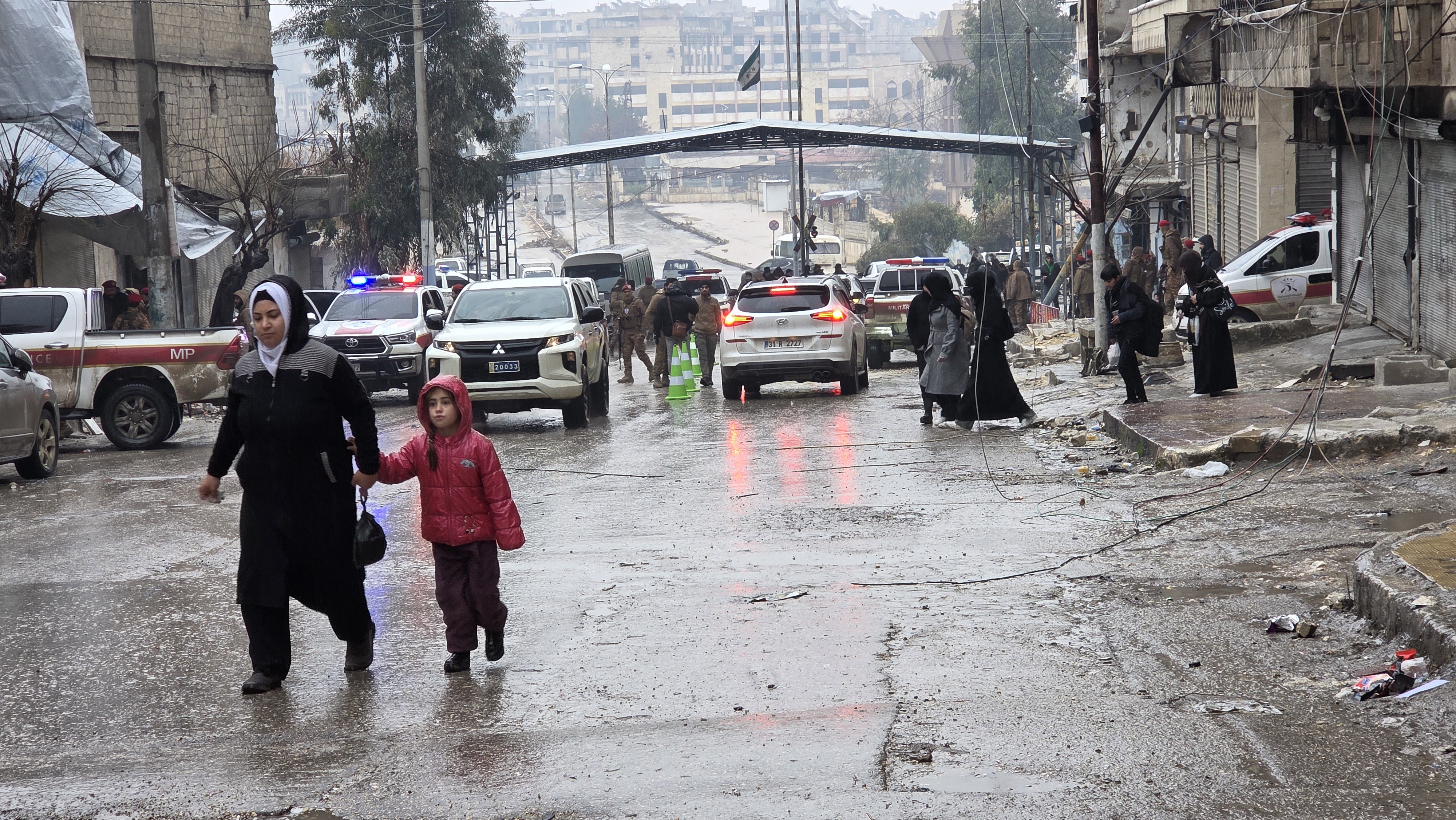Woman and child walk on a street with cars in the background