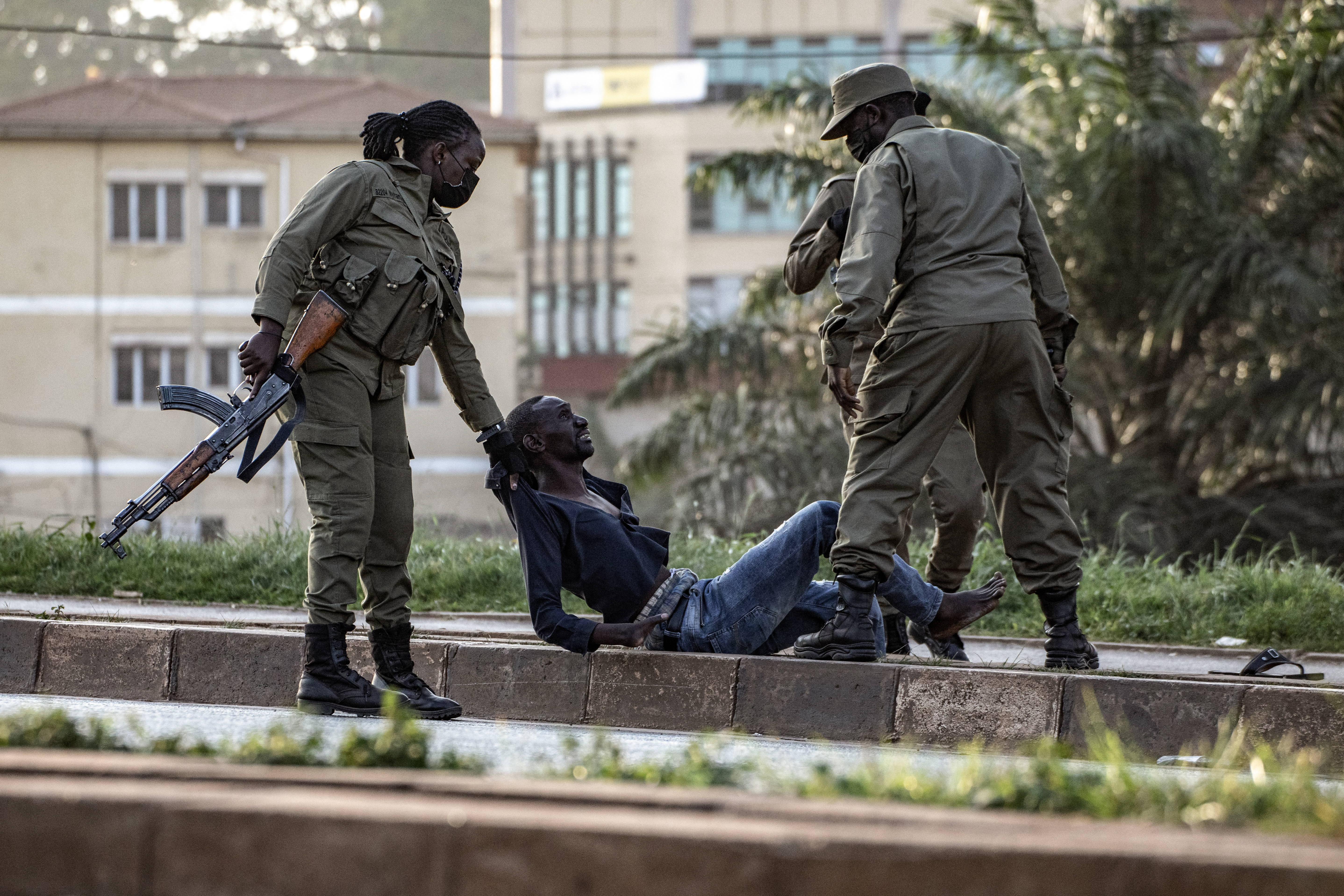 Police officers detain a voter on the ground near a polling station in Kampala