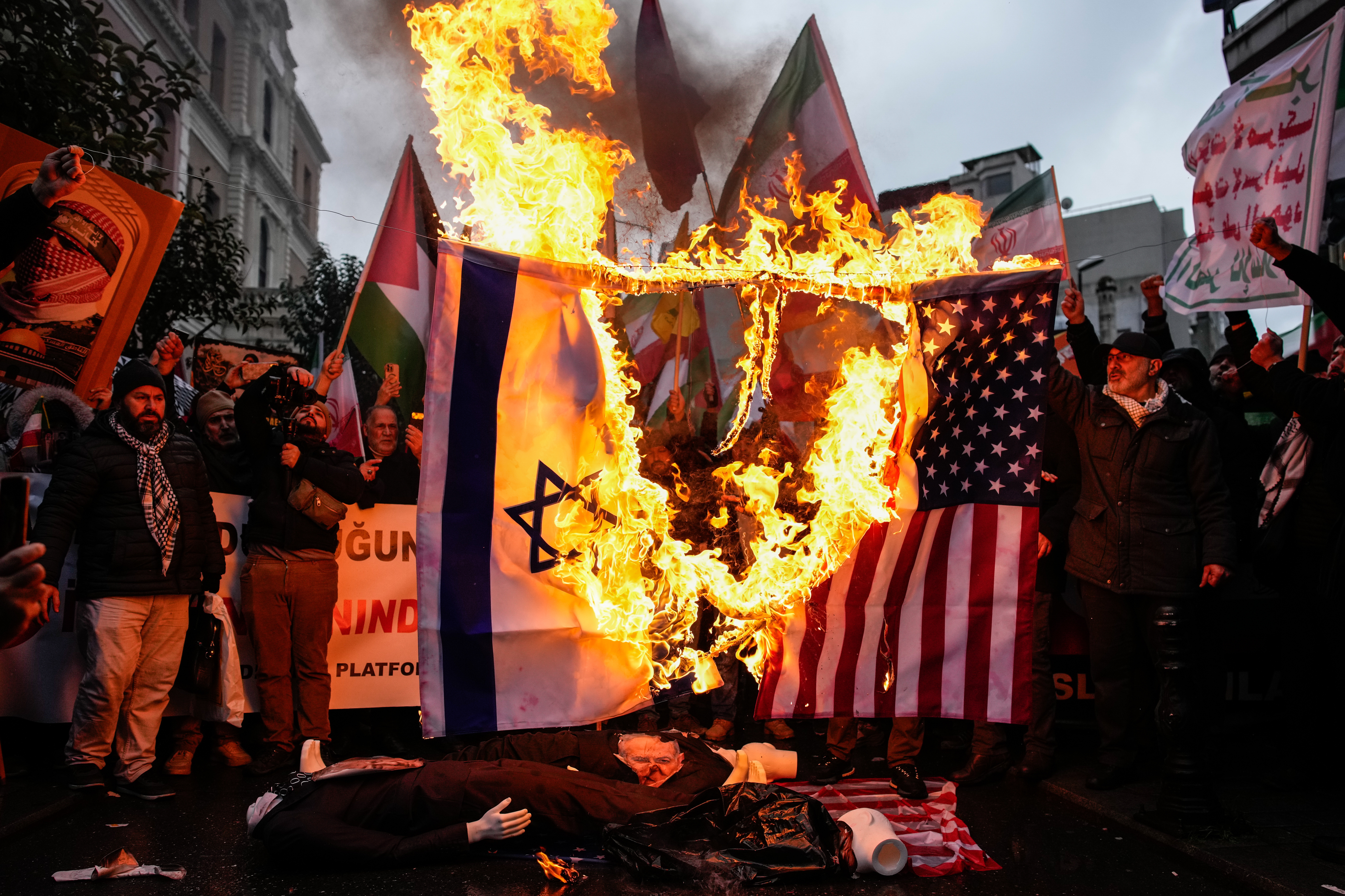 People burn U.S. and Israel flags during a rally in support of the Iranian government, in Istanbul, Turkey