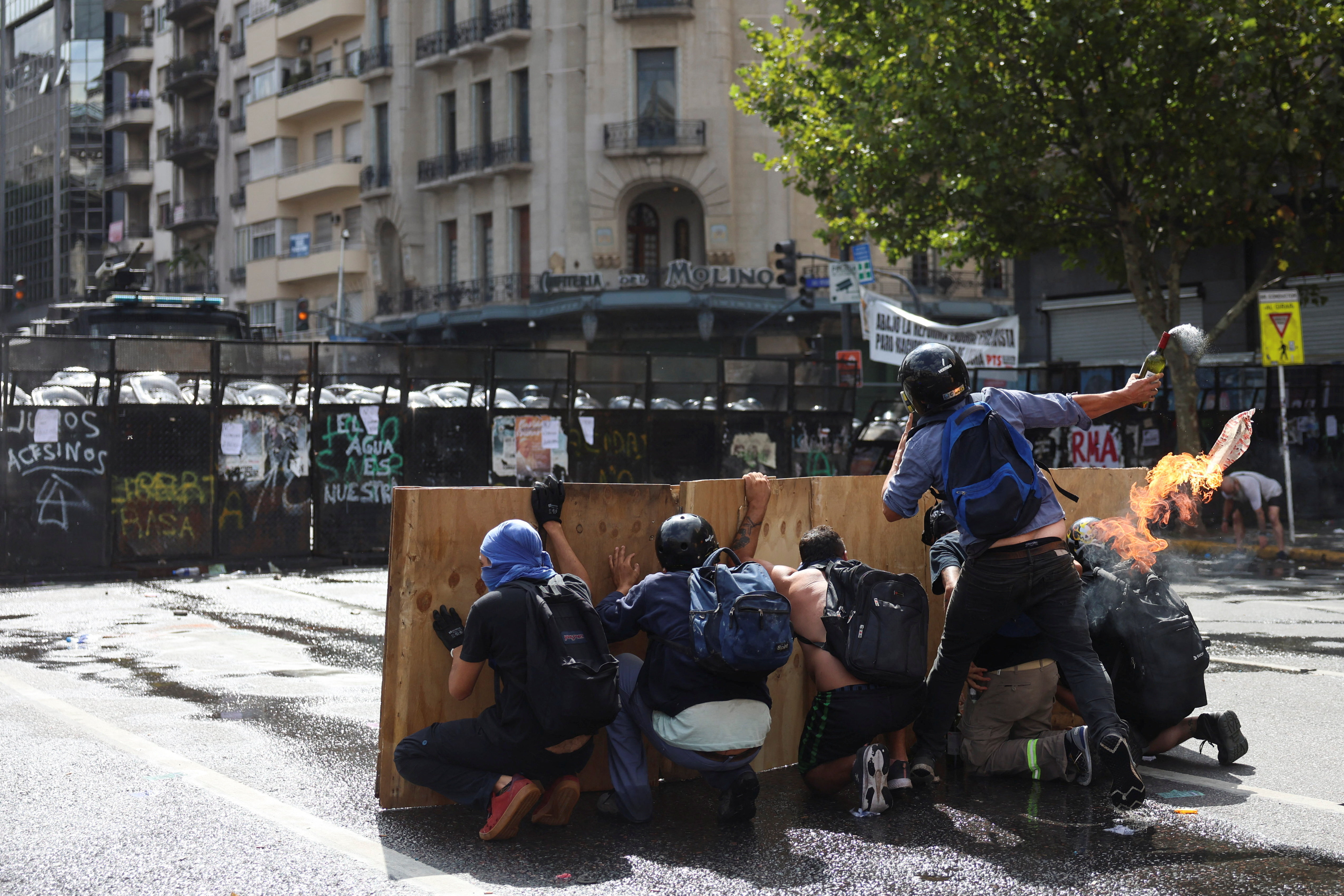 Protesters behind a barrier as they throw a molotov cocktail towards police