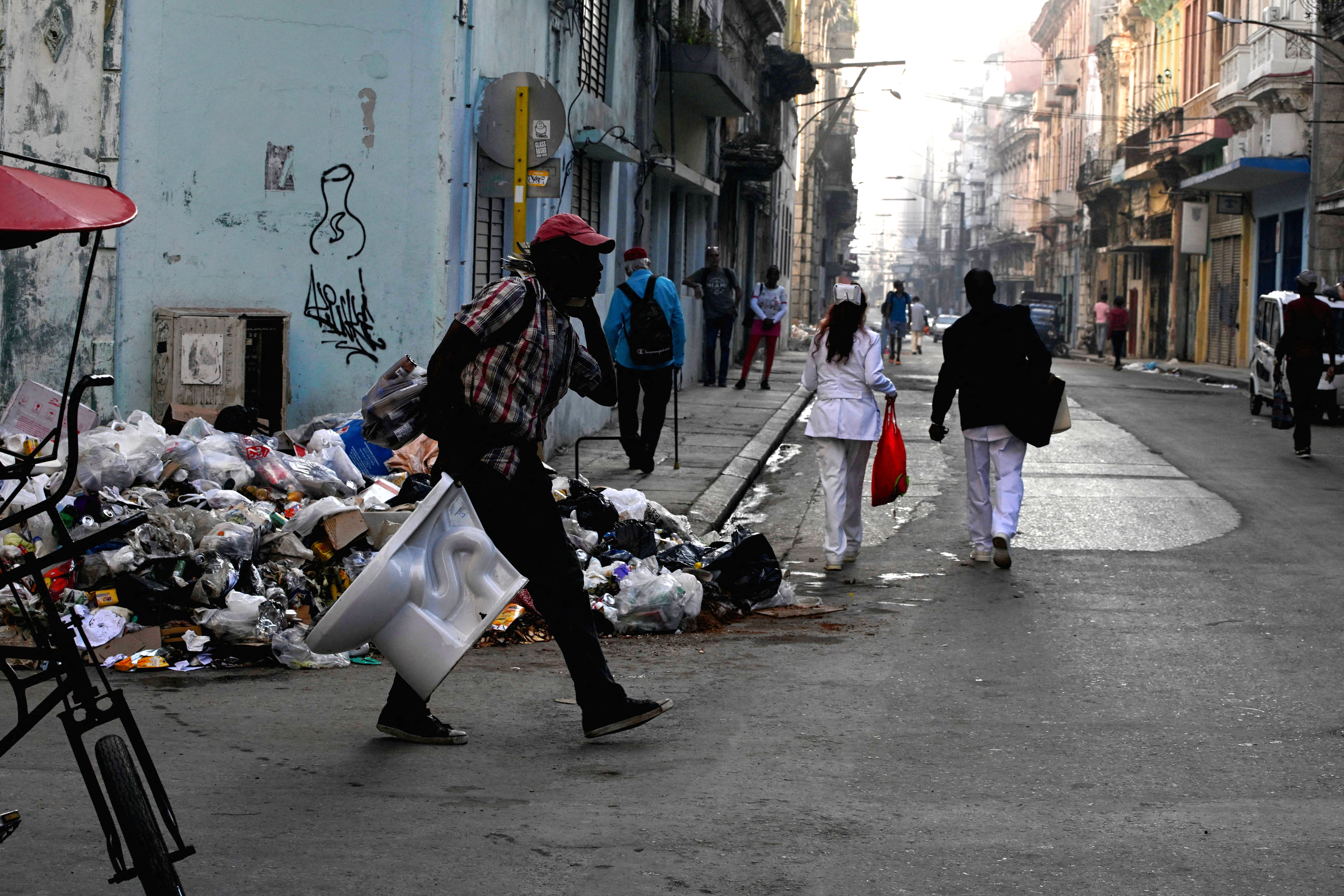 People walk next to trash on a street in downtown Havana, Cuba, February 16, 2026. REUTERS/Norlys Perez