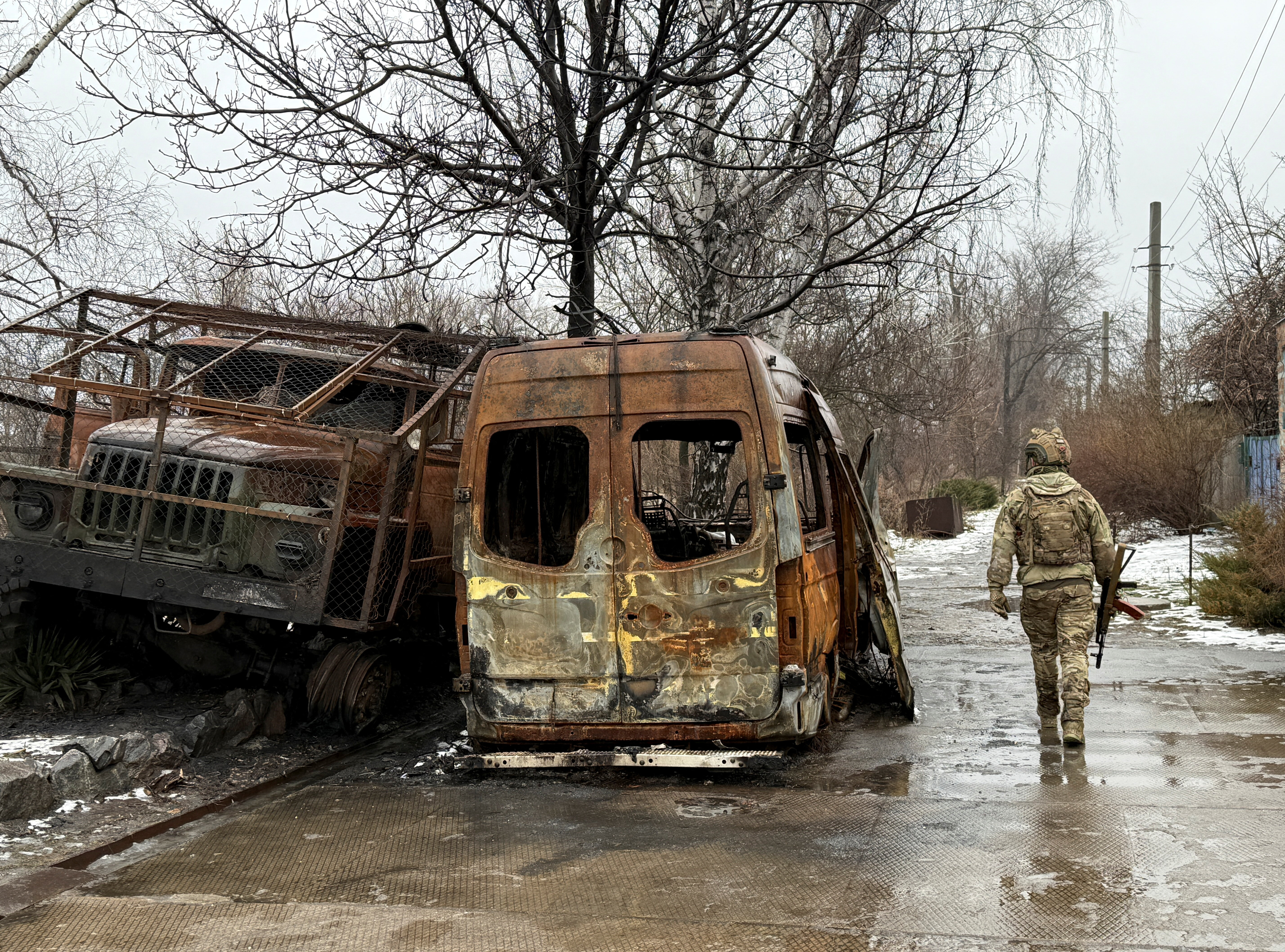A service member of the 93rd Kholodnyi Yar Separate Mechanized Brigade of the Ukrainian Armed Forces walks on a road near destroyed cars, amid Russia's attack on Ukraine, in the frontline town of Kostiantynivka in Donetsk region, Ukraine February 19, 2026. Picture taken with a mobile phone. REUTERS/Stringer