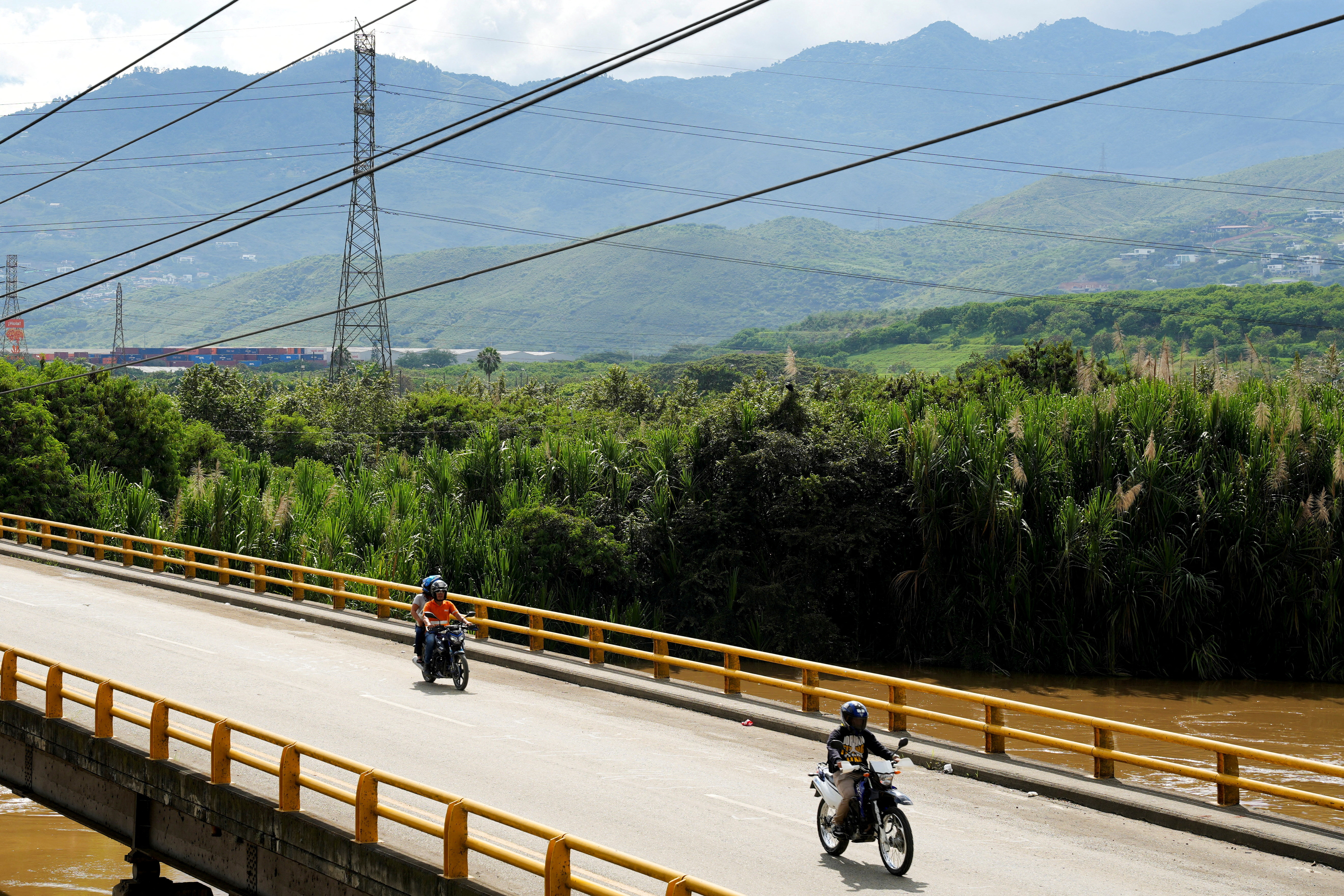 High-voltage power lines of Colombia's national public energy grid stretch over a roadway as motorcyclists cross a bridge, after Colombia announced it would suspend electricity sales to Ecuador. [FILE: Jair Coll/Reuters]