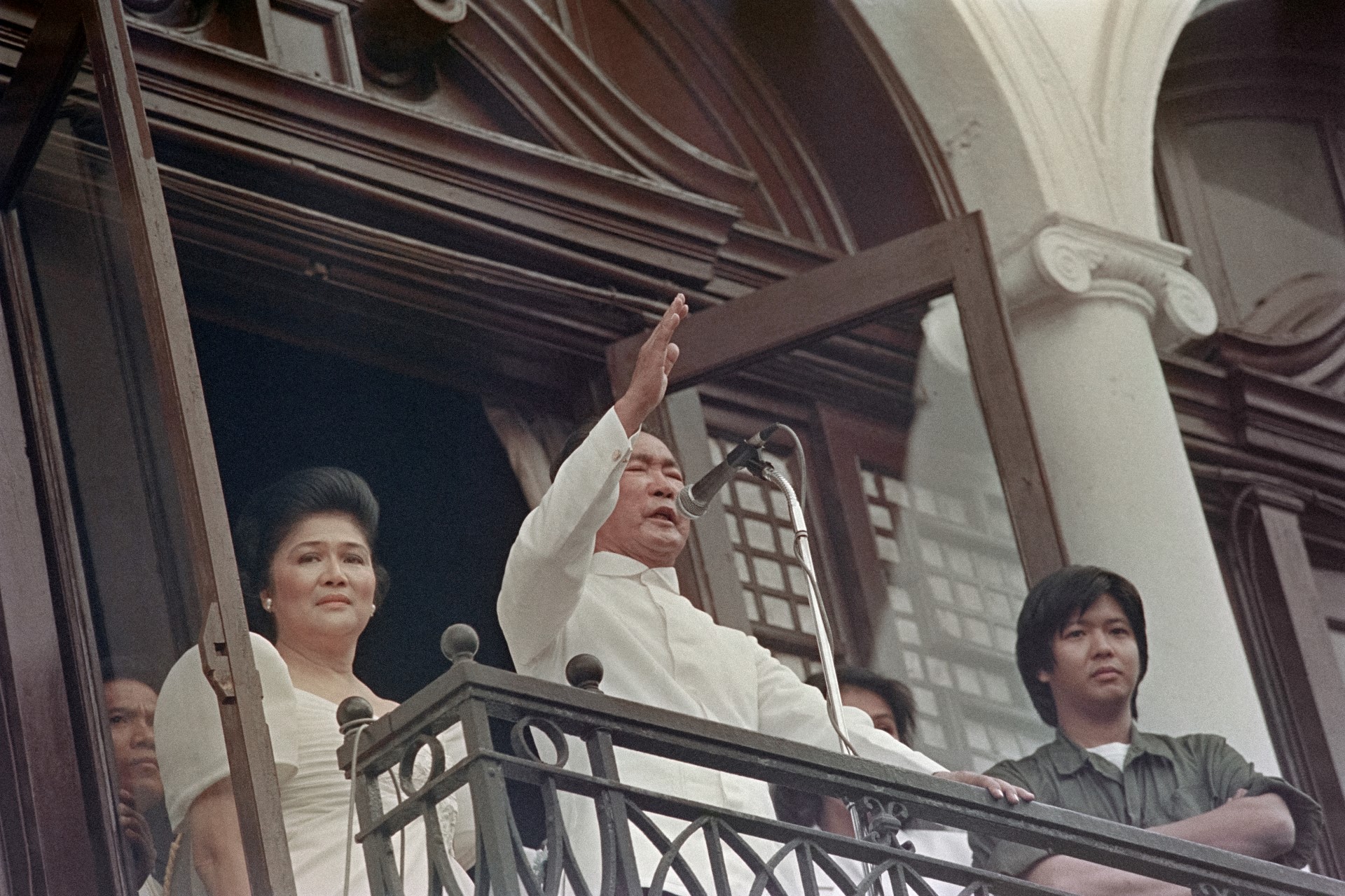 Young Ferdinand 'Bongbong' Marcos Jr, right, and his mother Imelda, left, look on as then-Philippine President Ferdinand Marcos, centre, waves goodbye to his supporters from the balcony of Malacanang Palace in Manila just hours before his removal from power and his family's exile to Hawaii on February 25, 1986