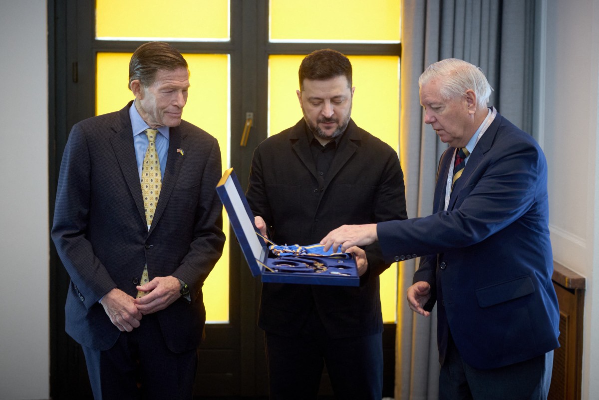 This handout photograph taken and released by the Ukrainian Presidential Press Service on February 14, 2026, shows Ukraine's President Volodymyr Zelensky (C) awarding US Senator Lindsey Graham (R) and US Senator Richard Blumenthal (L) with the Order of Prince Yaroslav the Wise, First Class during a meeting with senators of Congress at the 62nd Munich Security Conference (MSC) in Munich. (Photo by Handout / UKRAINIAN PRESIDENTIAL PRESS SERVICE / AFP) / RESTRICTED TO EDITORIAL USE - MANDATORY CREDIT "AFP PHOTO /HANDOUT / UKRAINIAN PRESIDENTIAL PRESS SERVICE" - NO MARKETING NO ADVERTISING CAMPAIGNS - DISTRIBUTED AS A SERVICE TO CLIENTS