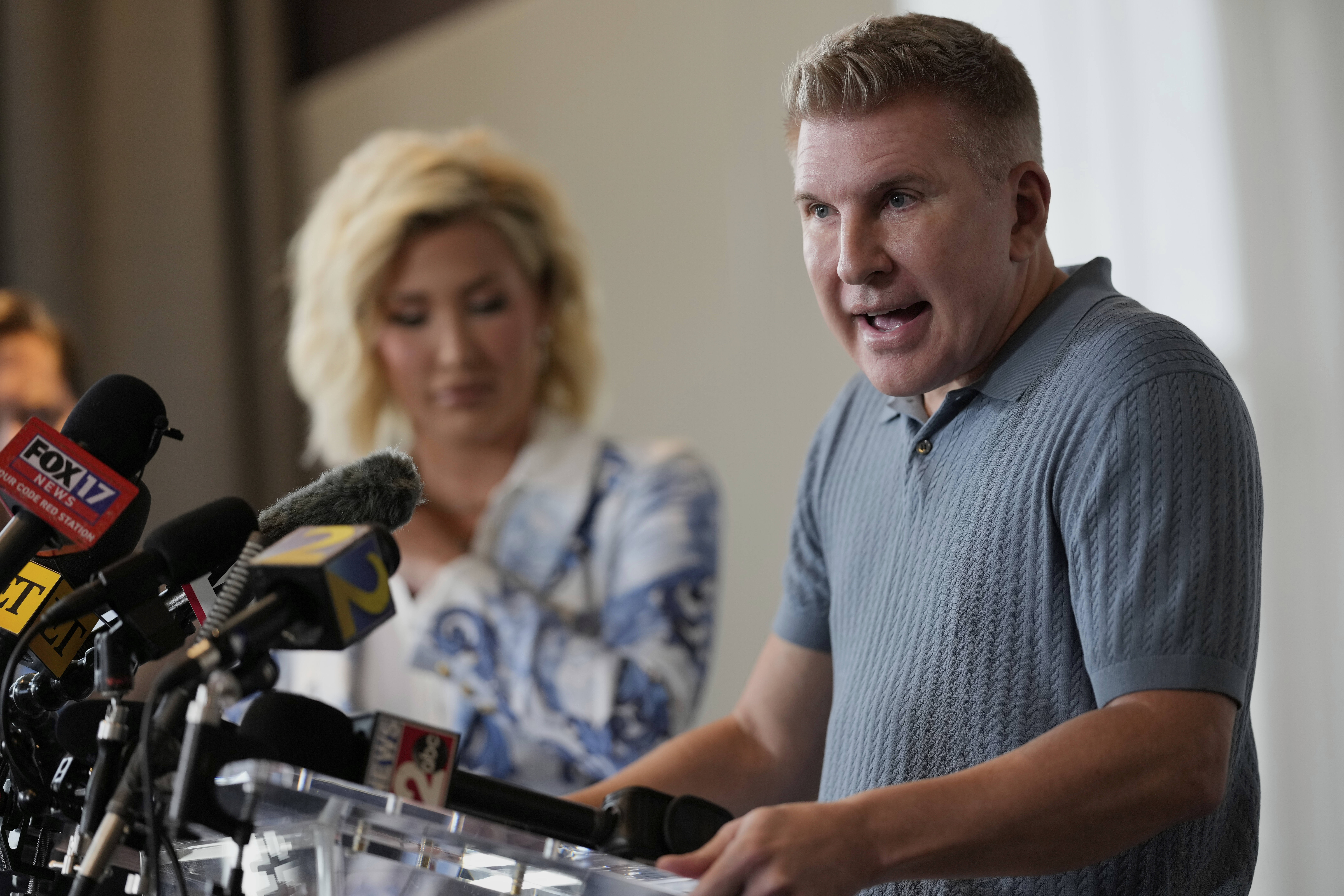 Todd Chrisley speaks at a podium next to his daughter Savannah