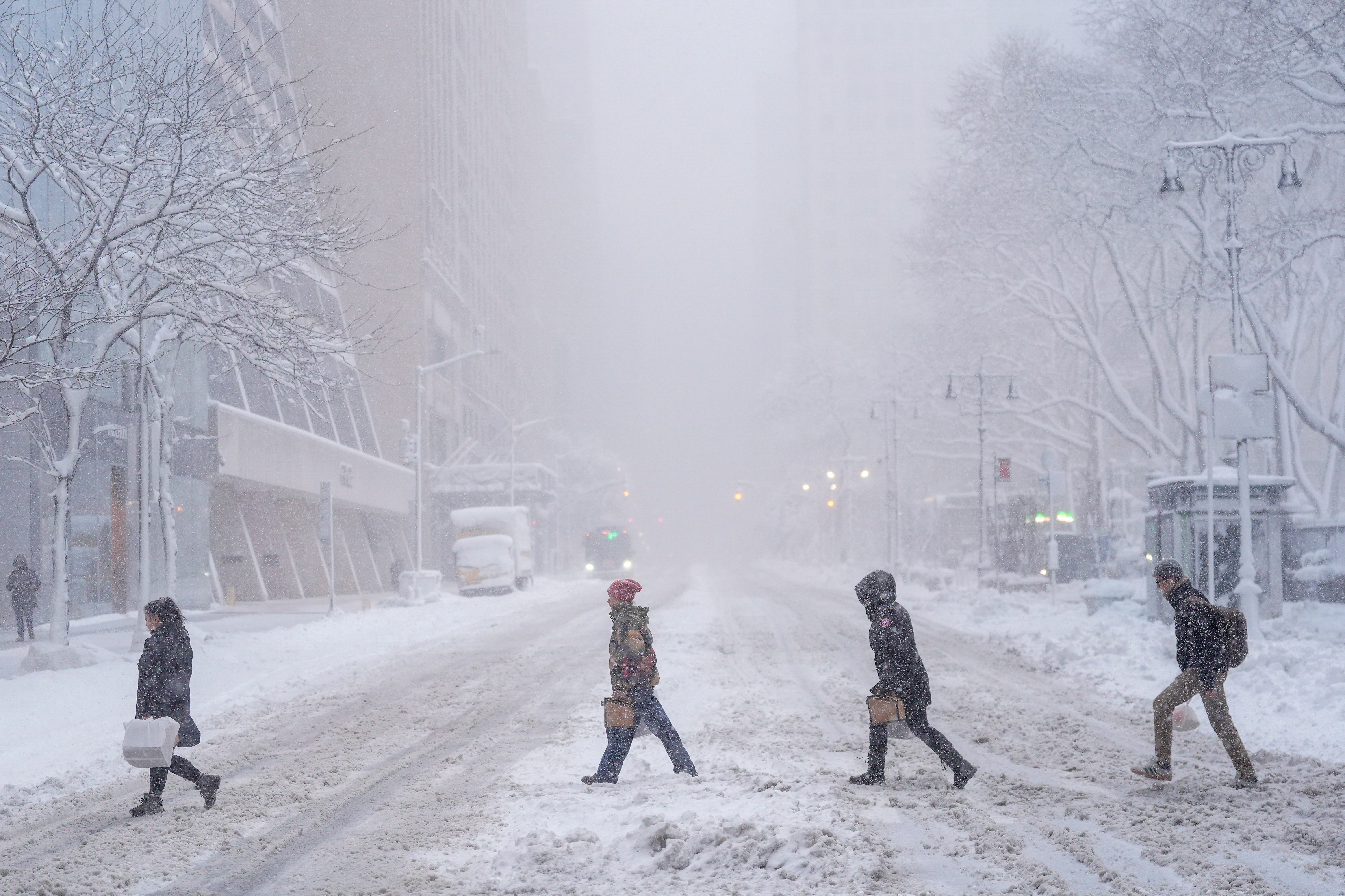 Pedestrians cross 42nd Street during a snowstorm, on February 23, 2026, in New York, US