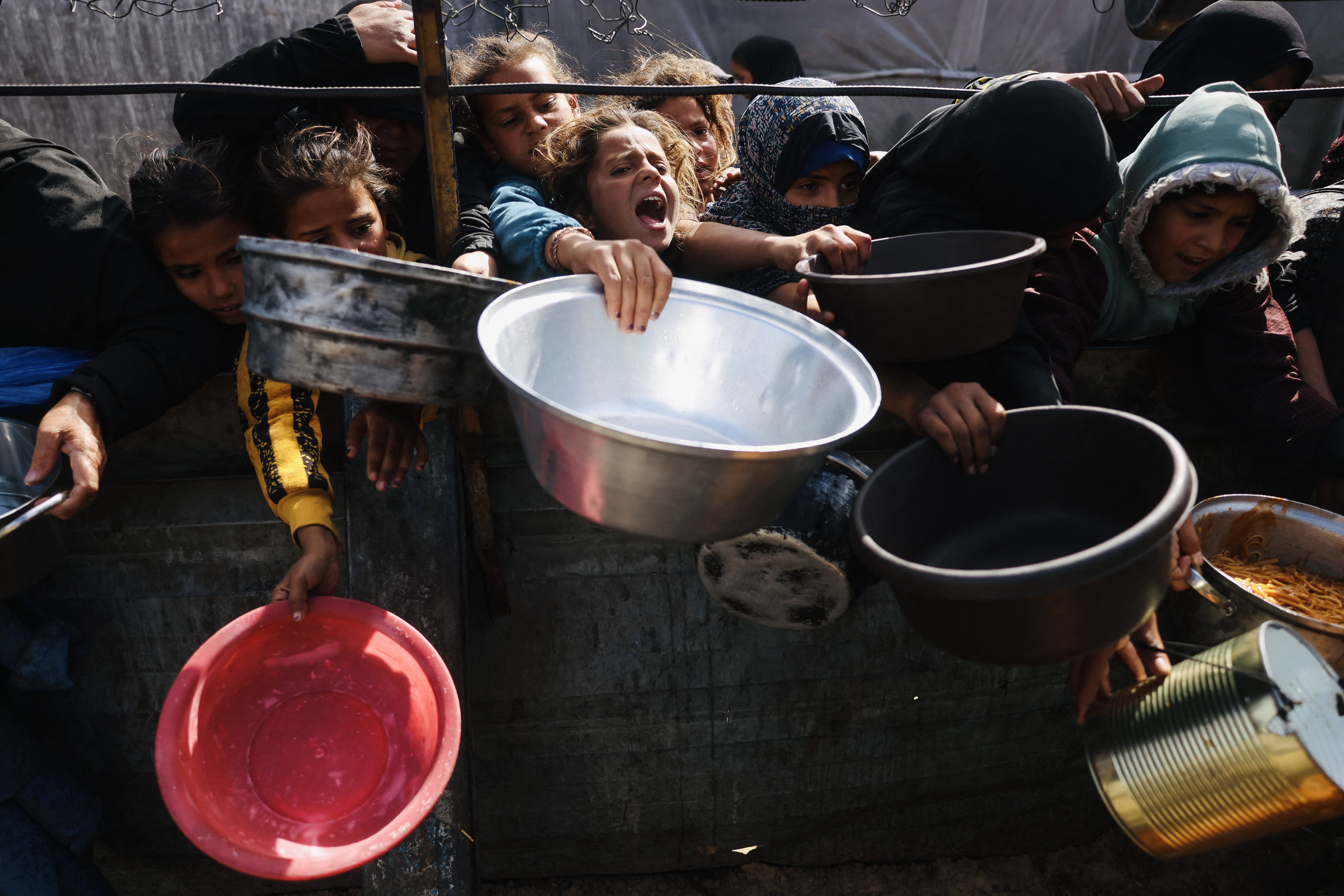 Young Palestinians struggle to receive donated food at a community kitchen in Khan Yunis in the southern Gaza Strip on February 7, 2026.