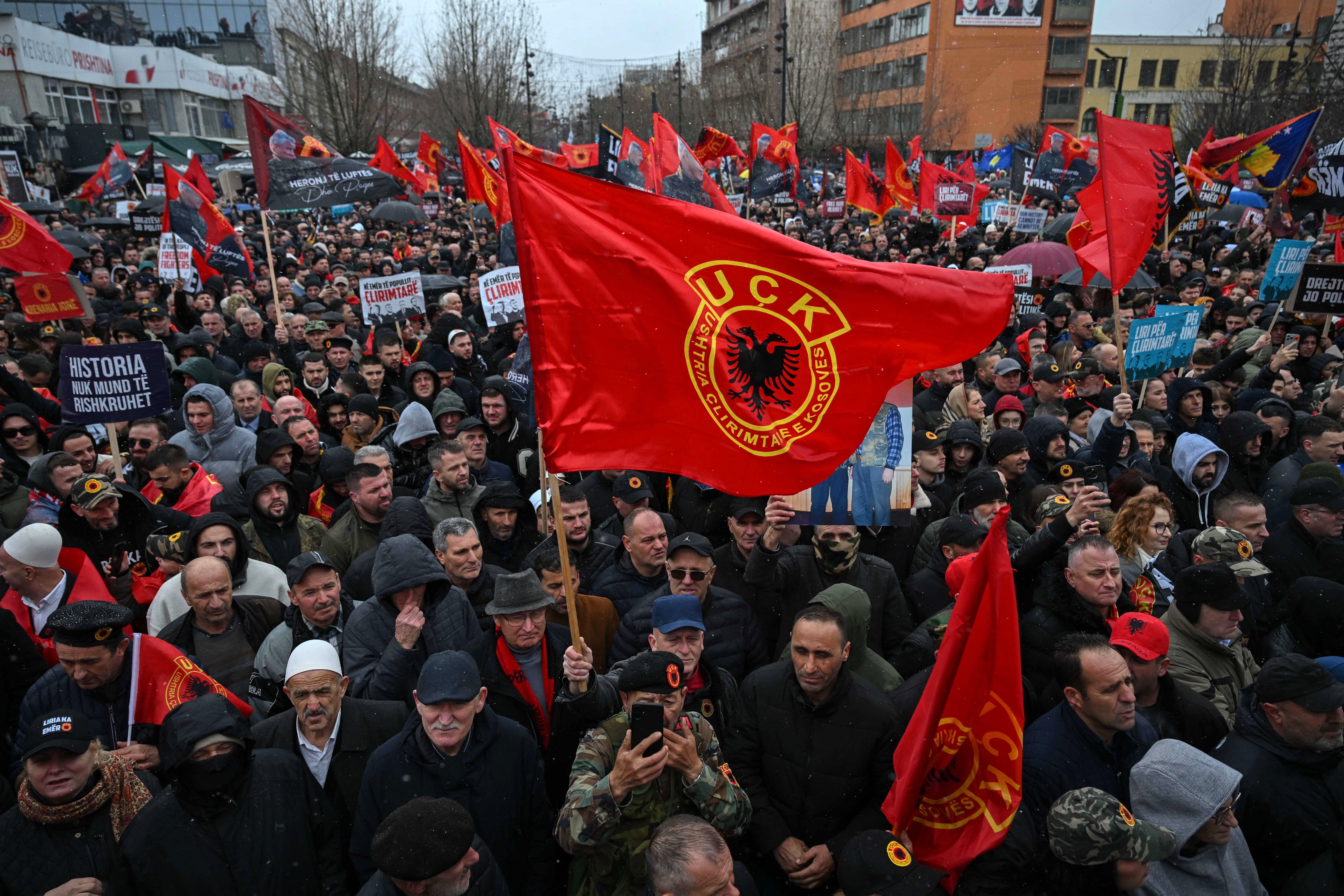 A protester waves a KLA flag as Kosovo Albanians demonstrate in support of former Kosovo Liberation Army (KLA) leaders, including former Kosovo President Hashim Thaci, on trial at The Hague's international tribunal in downtown Pristina on February 17, 2026. (Photo by Armend NIMANI / AFP)