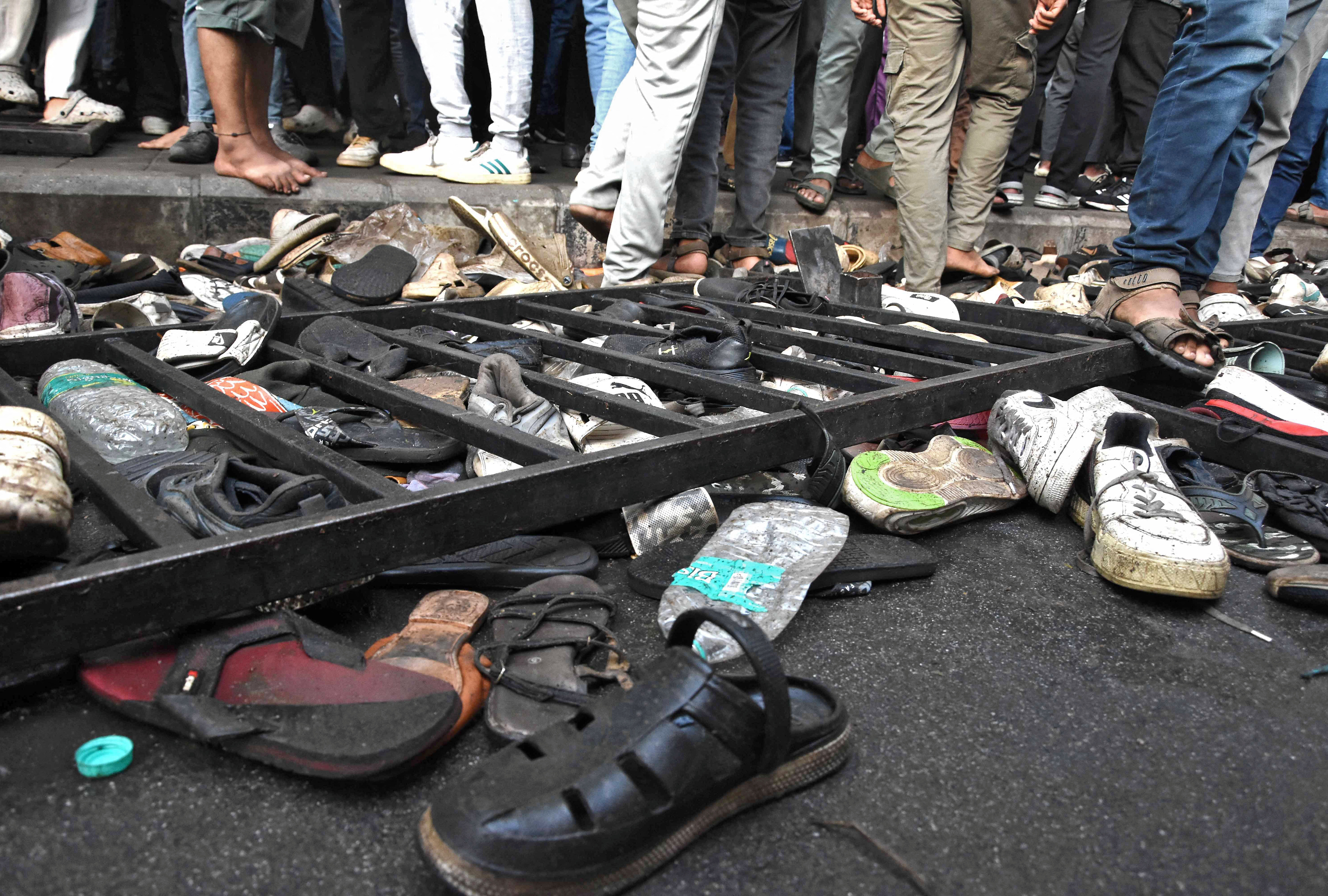 People walk past shoes left behind following a stampede outside a cricket stadium in Bengaluru, India