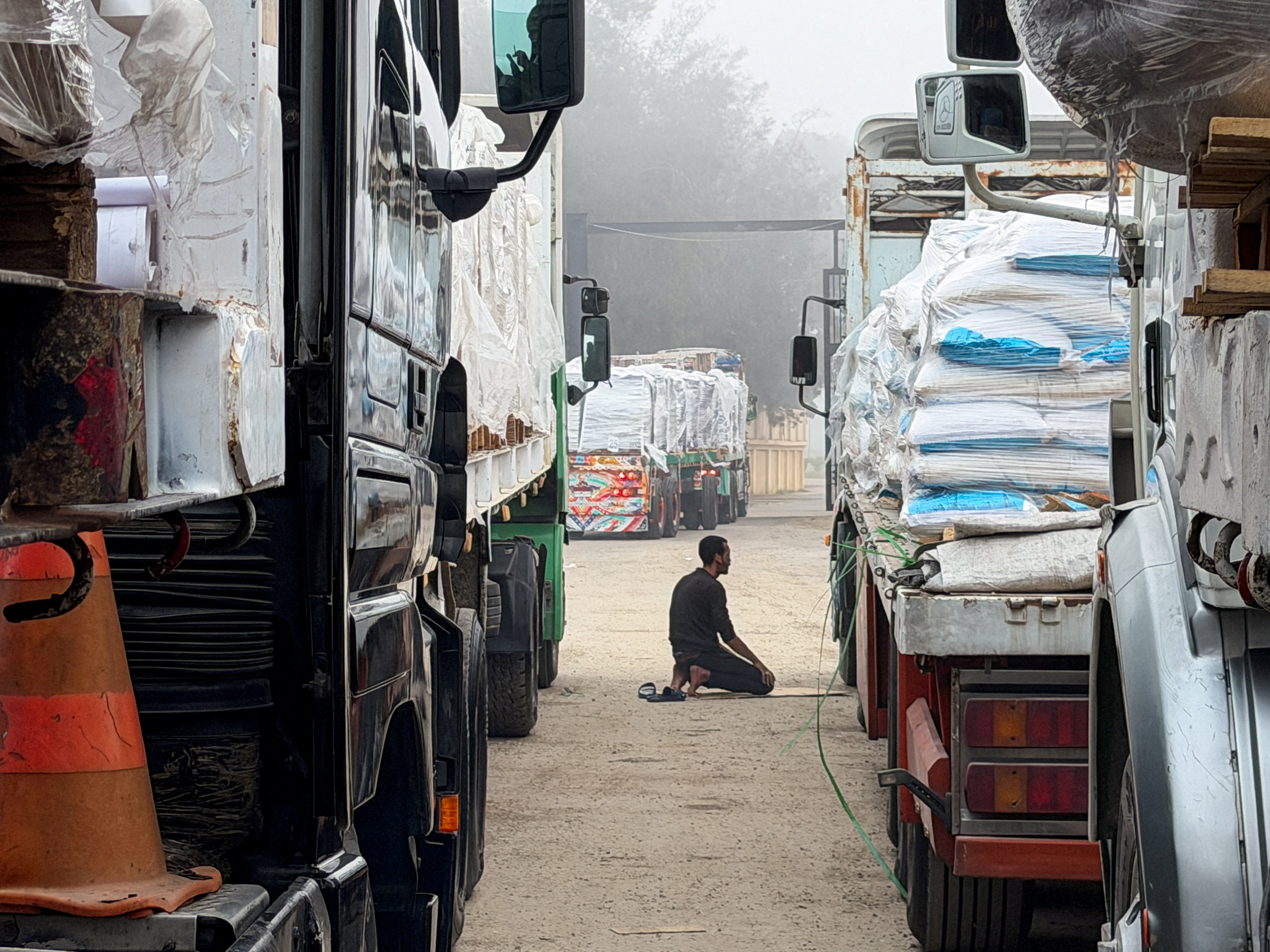 FILE PHOTO: An Egyptian man prays next to trucks carrying humanitarian aid and fuel lined up at the Rafah border to cross into the Gaza Strip, on the Egyptian side, in Rafah, Egypt, February 10, 2026. Picture taken with a mobile phone. REUTERS/Stringer/File Photo