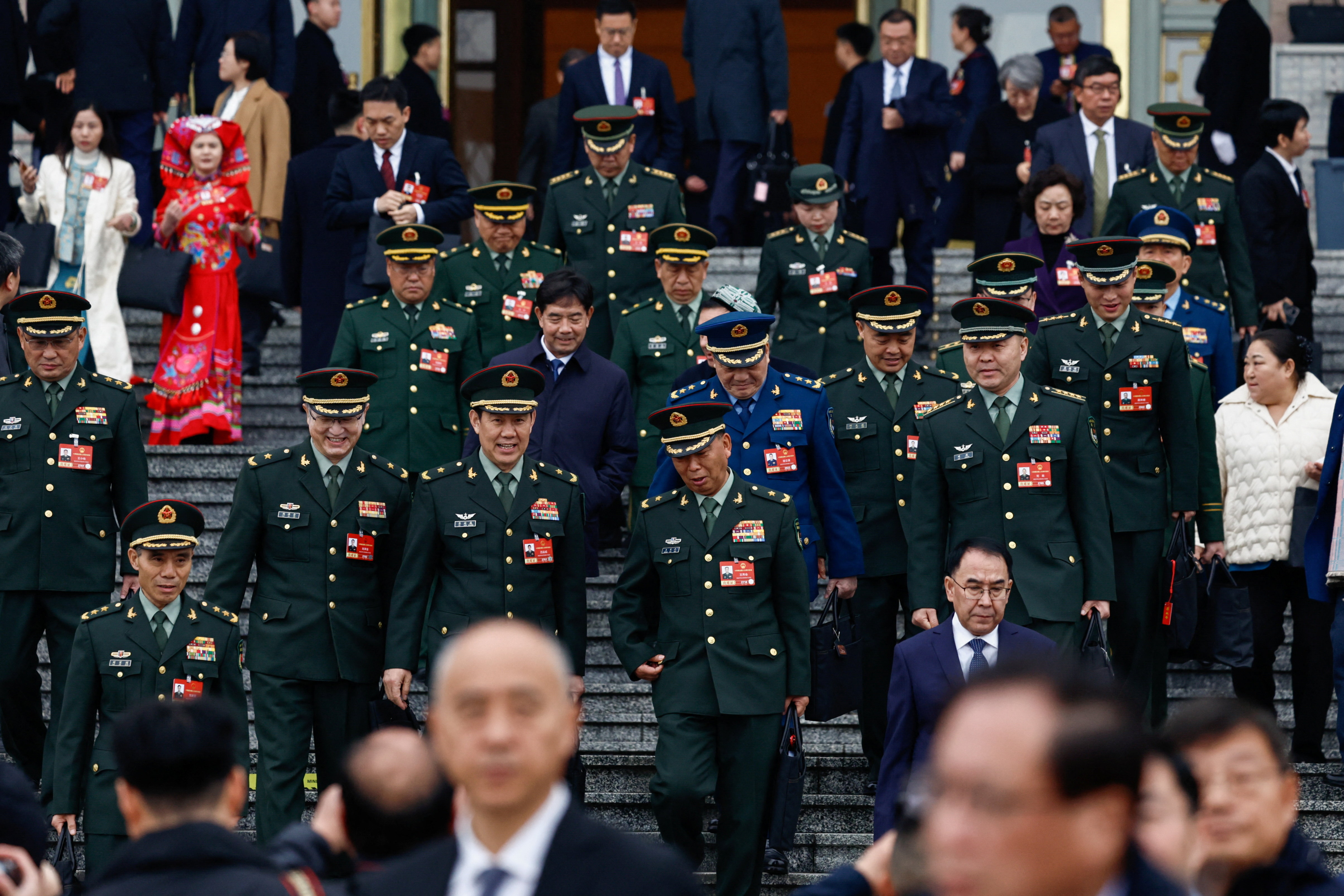 Military delegates walk down a staircase as they leave a building.