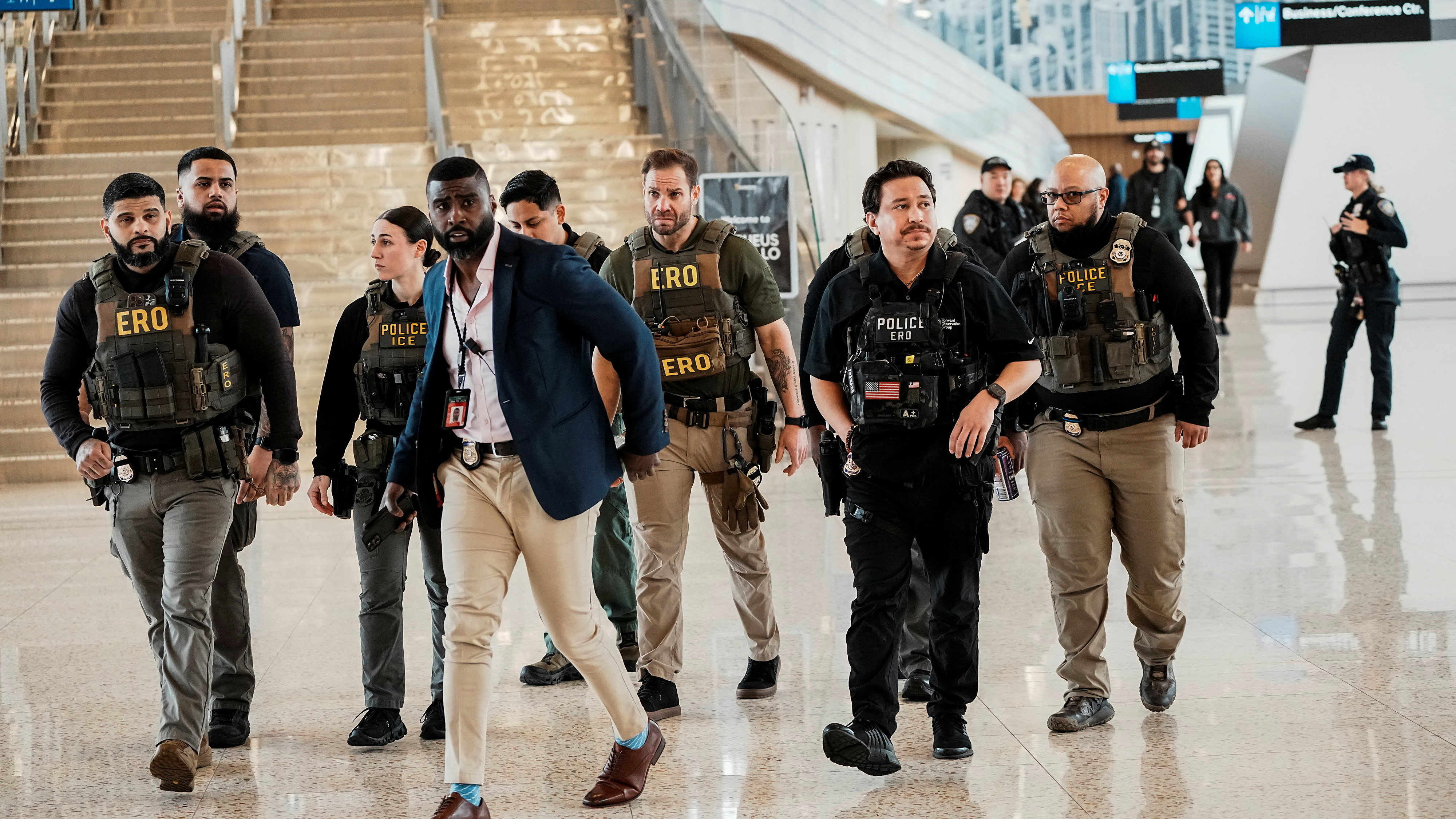 Immigration and Customs Enforcement (ICE) agents patrol at an airport.