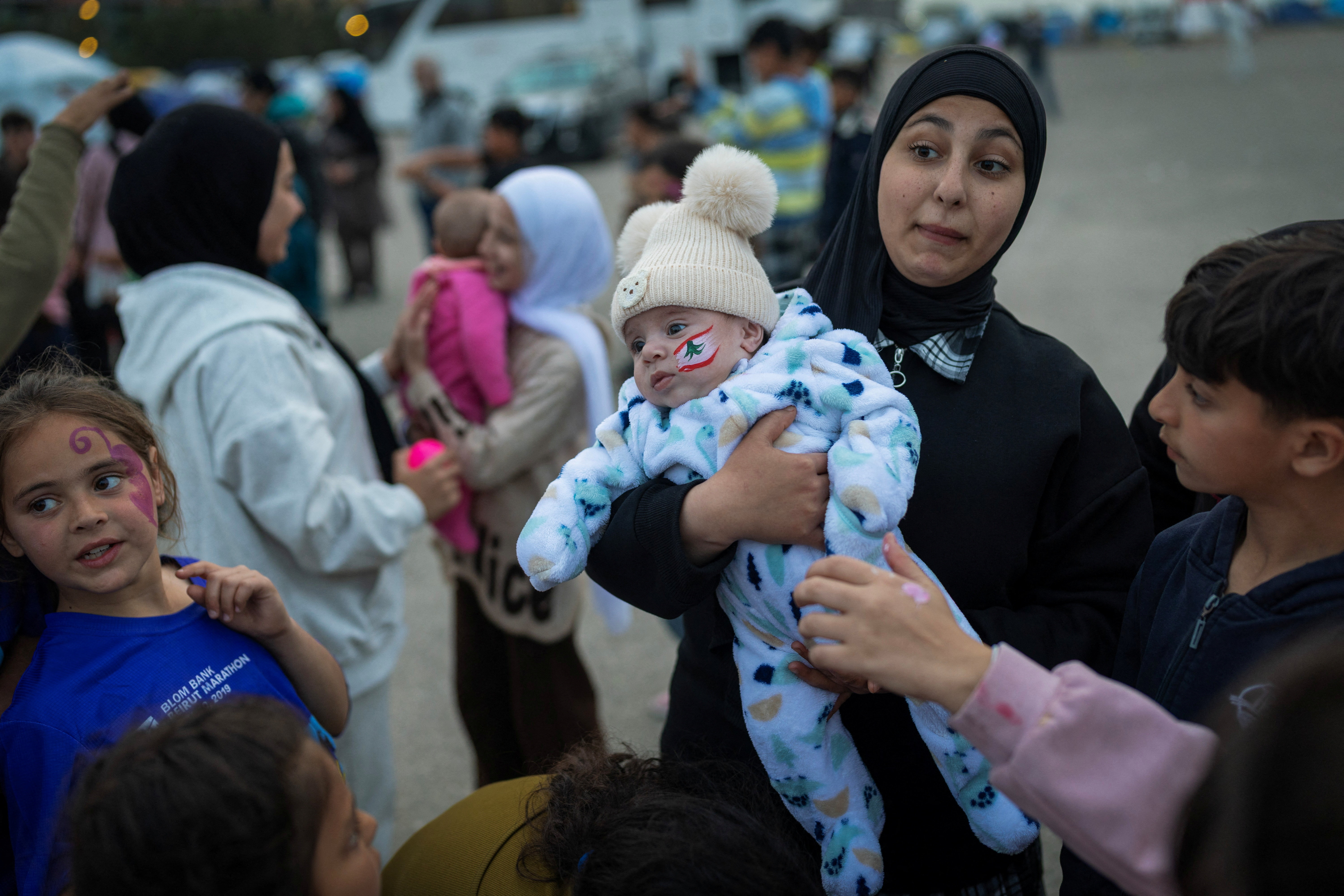 A Lebanese woman holds her nephew as she stands outside their tent, at a temporary encampment for displaced people, amid escalating hostilities between Israel and Hezbollah