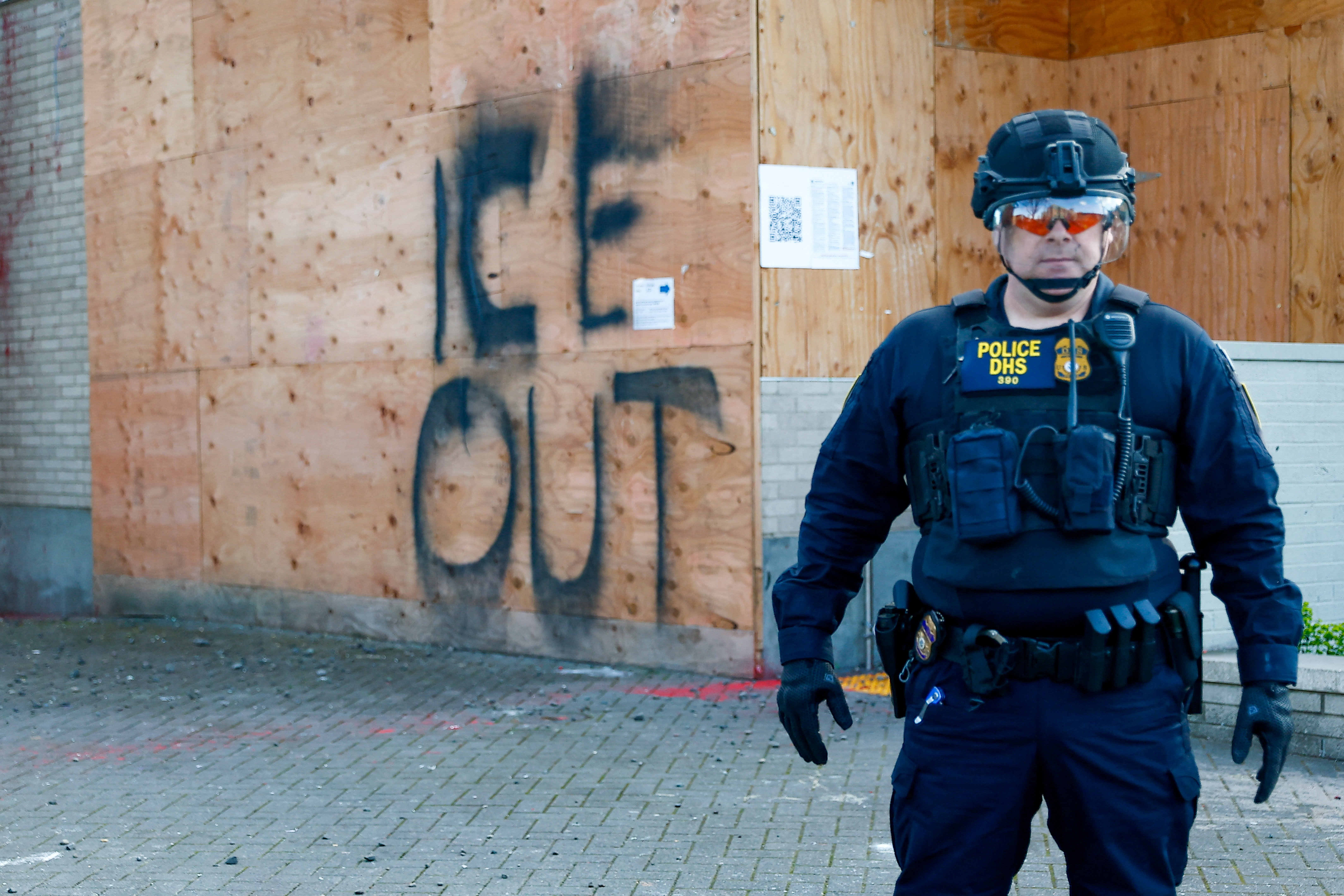 Agent standing in front of wall that says ICE out