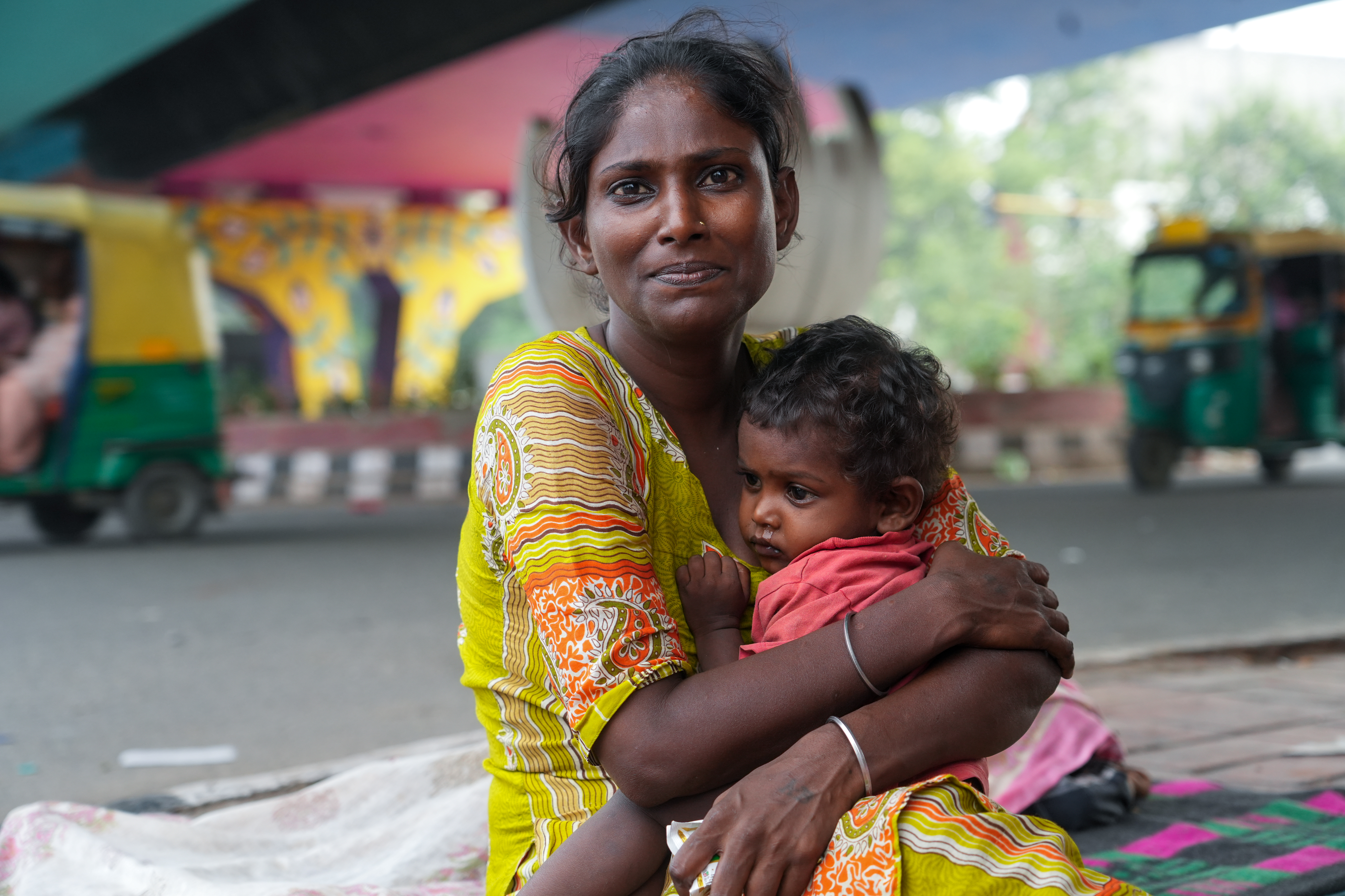 Soni, 2, rests in her mother Abida’s arms as fever keeps her weak and restless.Abida, originally from Assam, has lived on Delhi’s streets since childhood.Two of her children were killed last year when a speeding car ran over them while the family was asleep near the Hazrat Nizamuddin roadside. [Suhail Bhat/Al Jazeera]