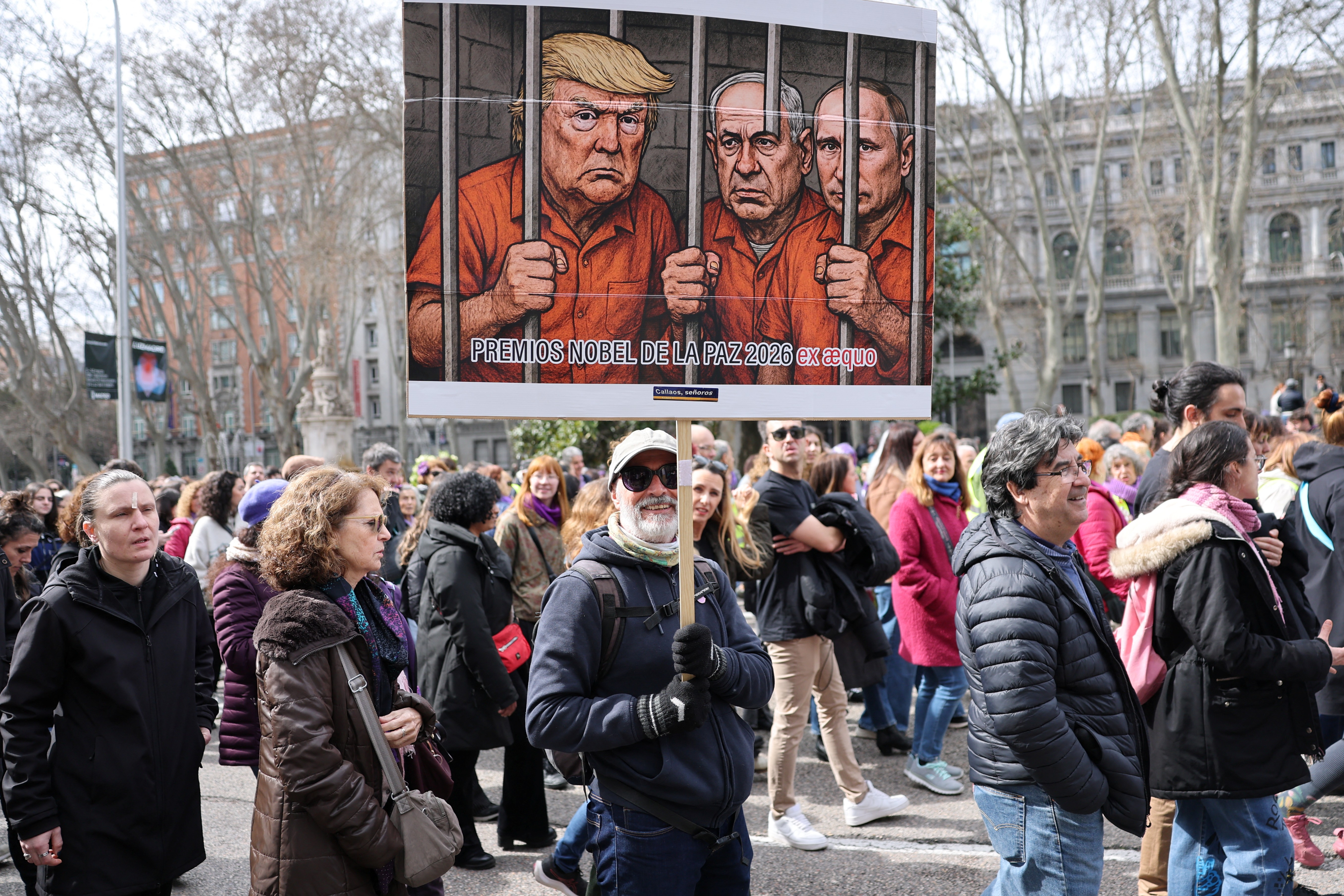 A man holds a banner mocking US President Donald Trump, Israeli Prime Minister Benjamin Netanyahu and Russia's President Vladimir Putin