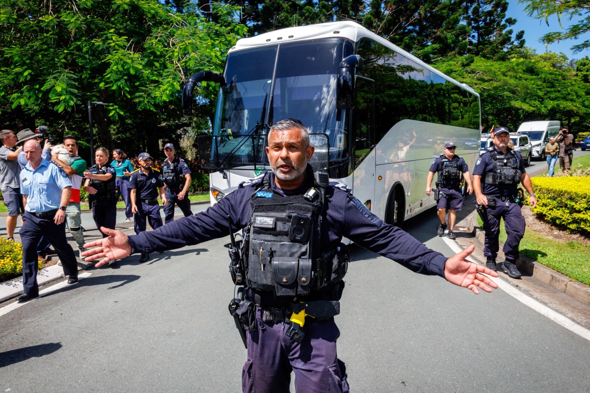 Police officers clear the road for a departing bus.