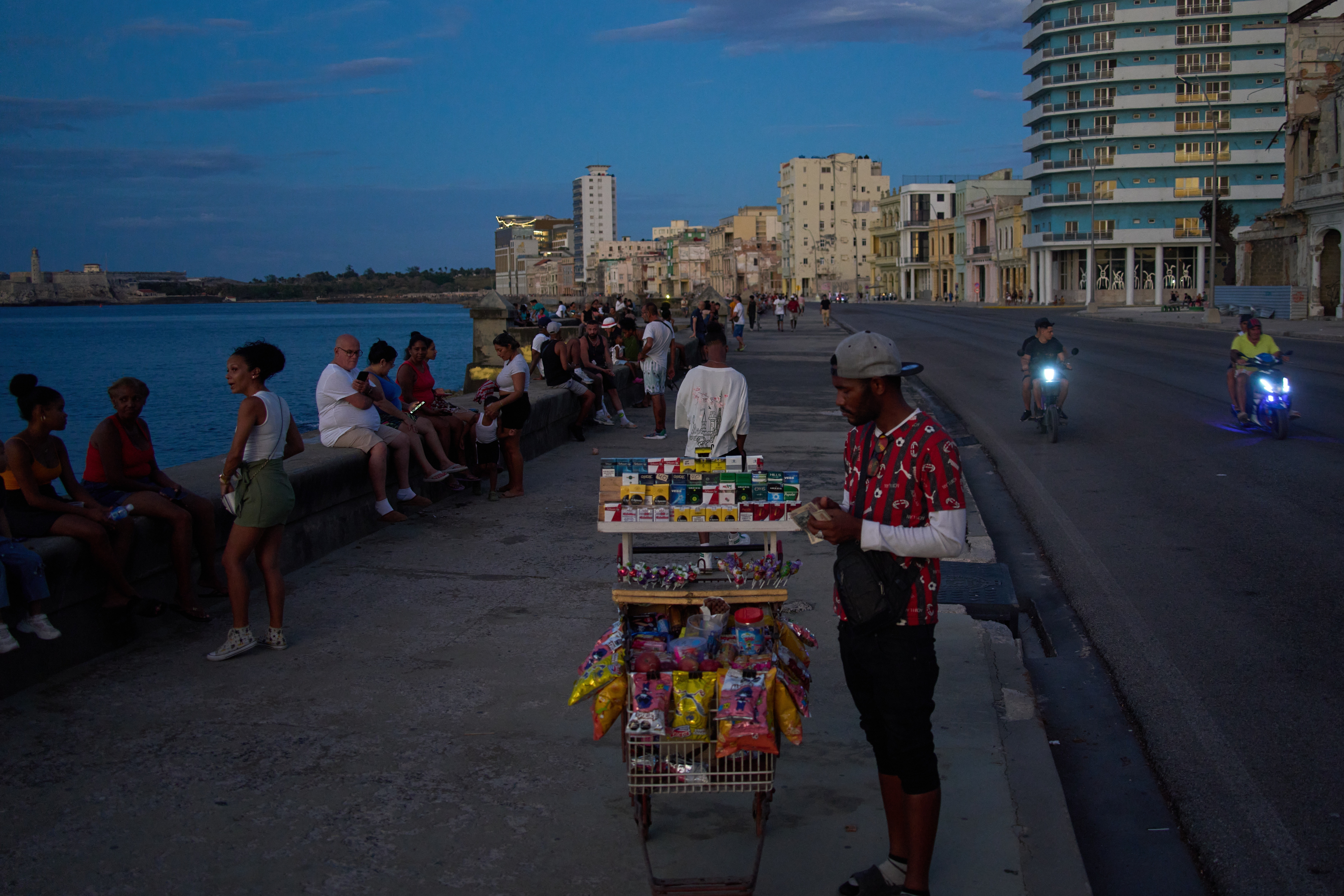 A street vendor waits for customers on the Malecón during a blackout in Havana