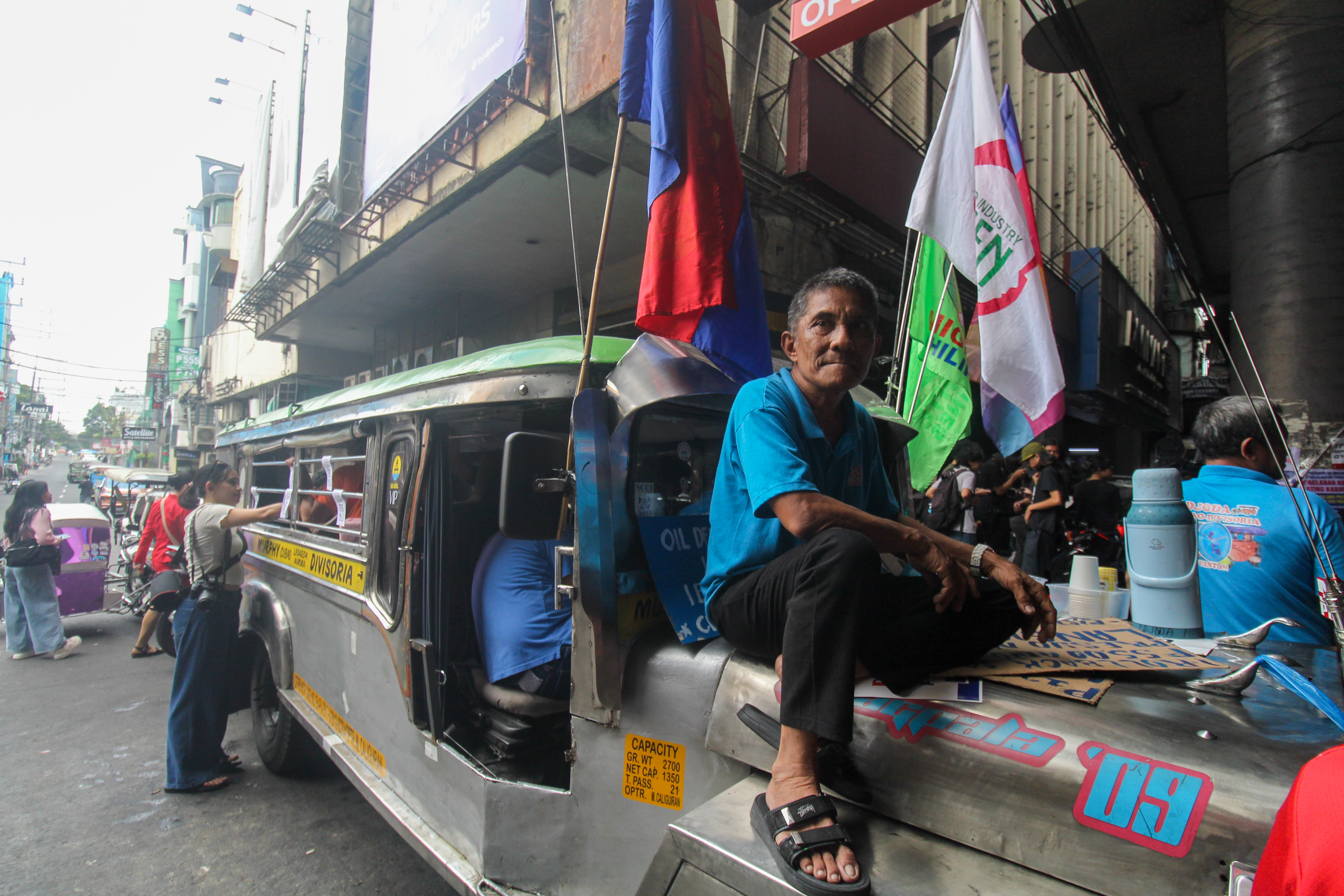 A driver sits on the bonnet of his jeepney in Manila amid protests in the Philippine capital over rising fuel prices [Michael Beltran/Al Jazeera]