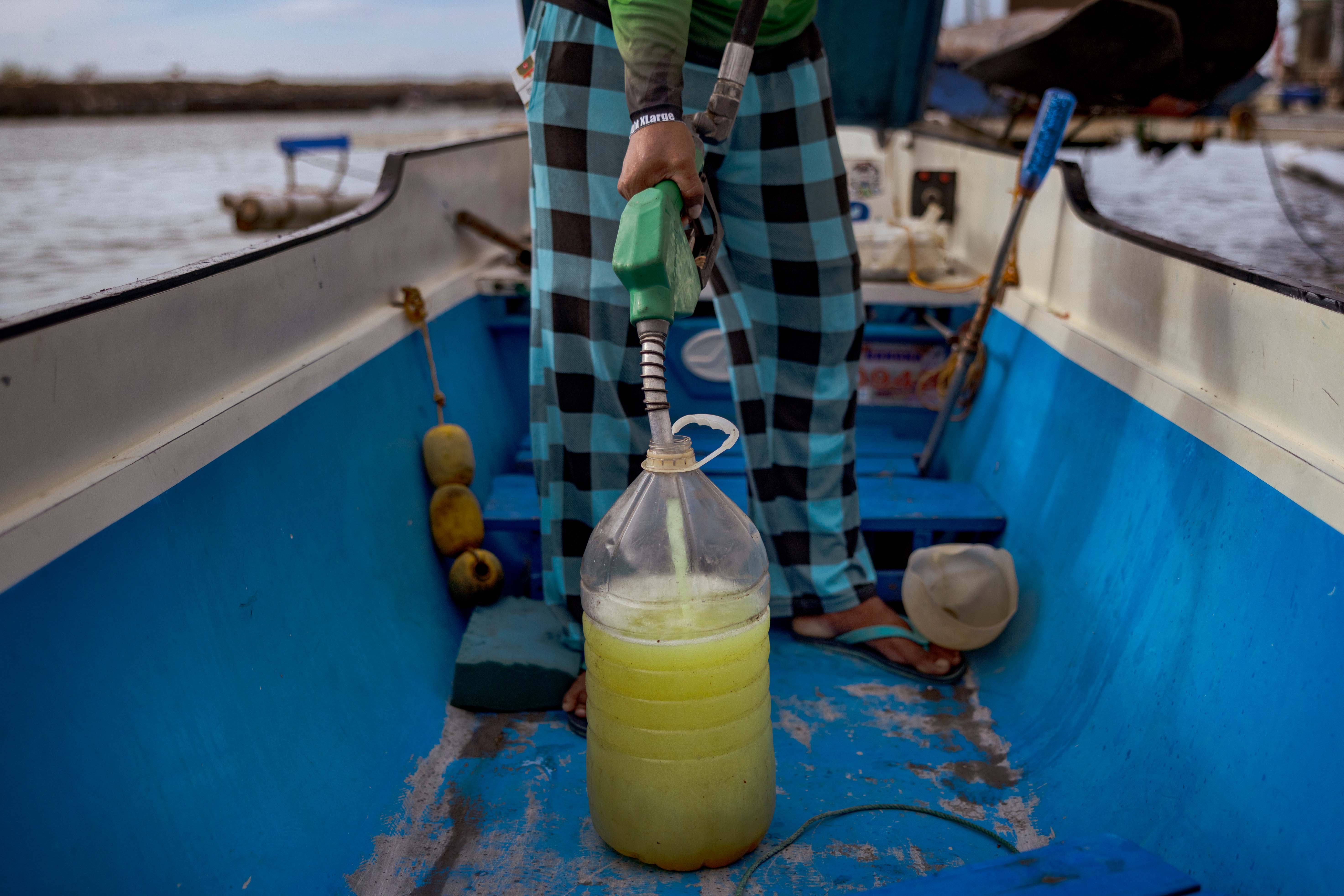 A fisherman buys fuel at a riverside gas station