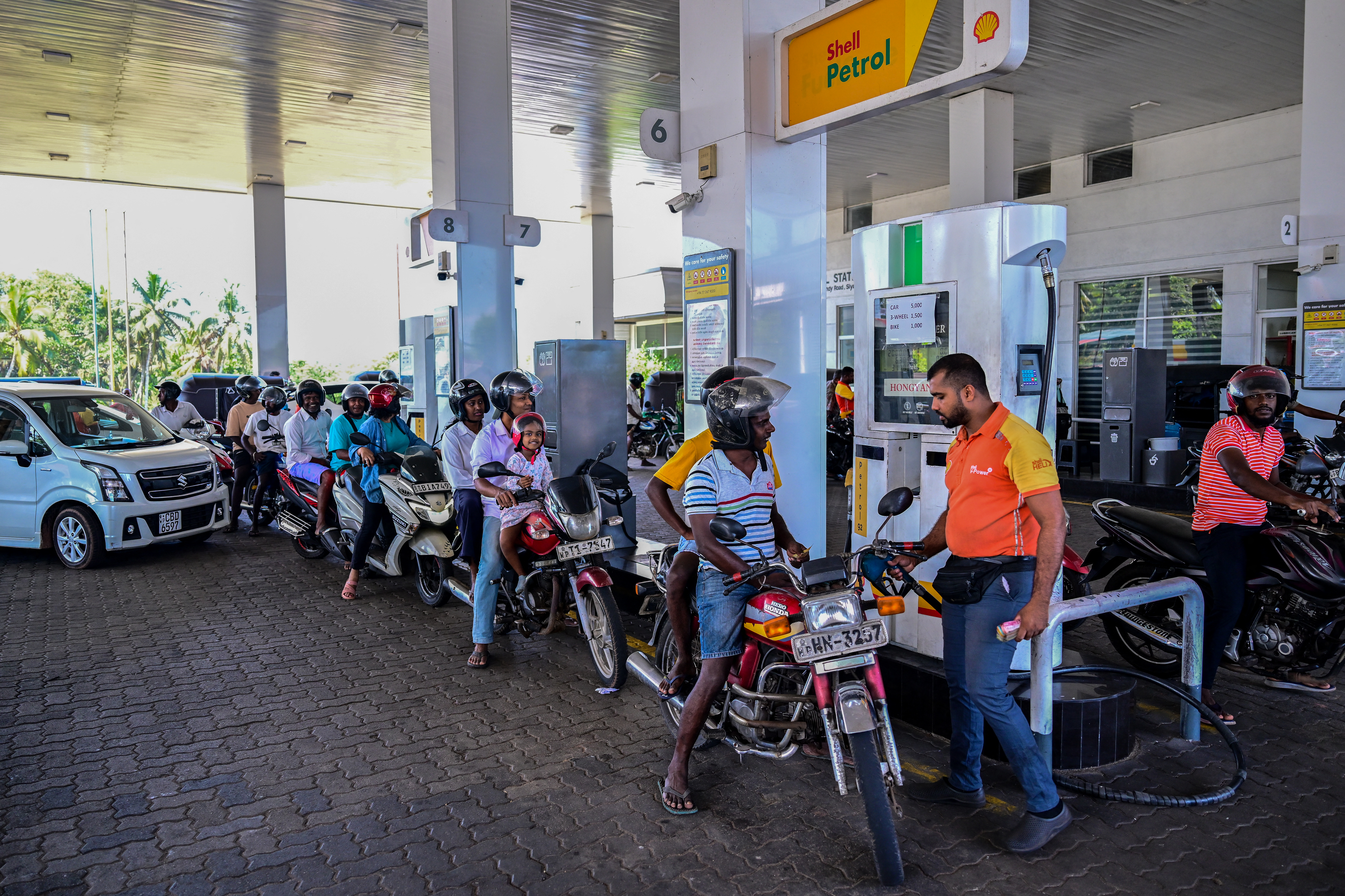 People wait in a queue to refuel their vehicles at a filling station in Biyagama, Sri Lanka