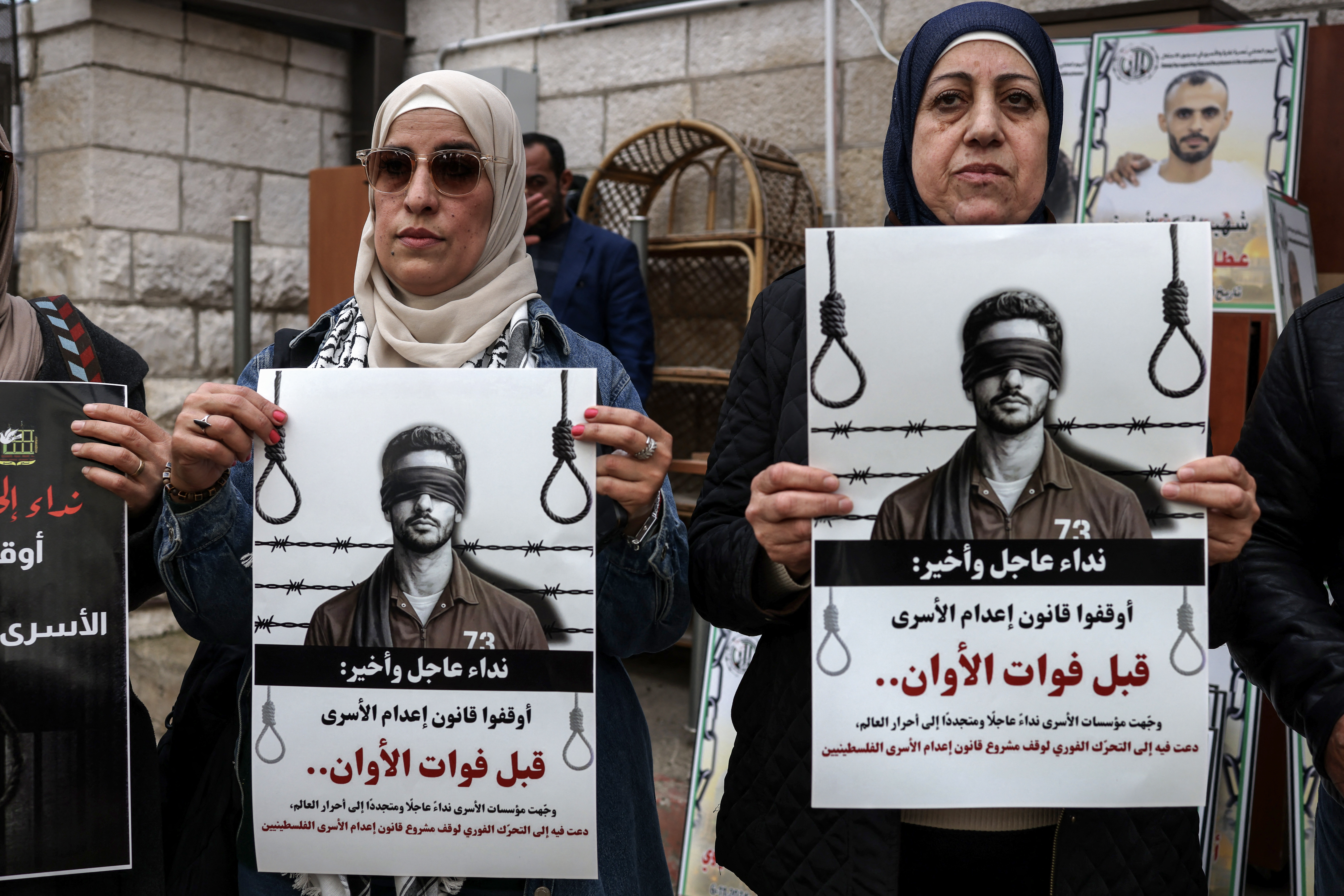 Protesters hold placards outside the Red Cross offices in Ramallah, in the Israeli-occupied West Bank, on March 31, 2026, during a rally against a bill approved by Israel's parliament that would allow the execution of Palestinians convicted on terror charges for deadly attacks.