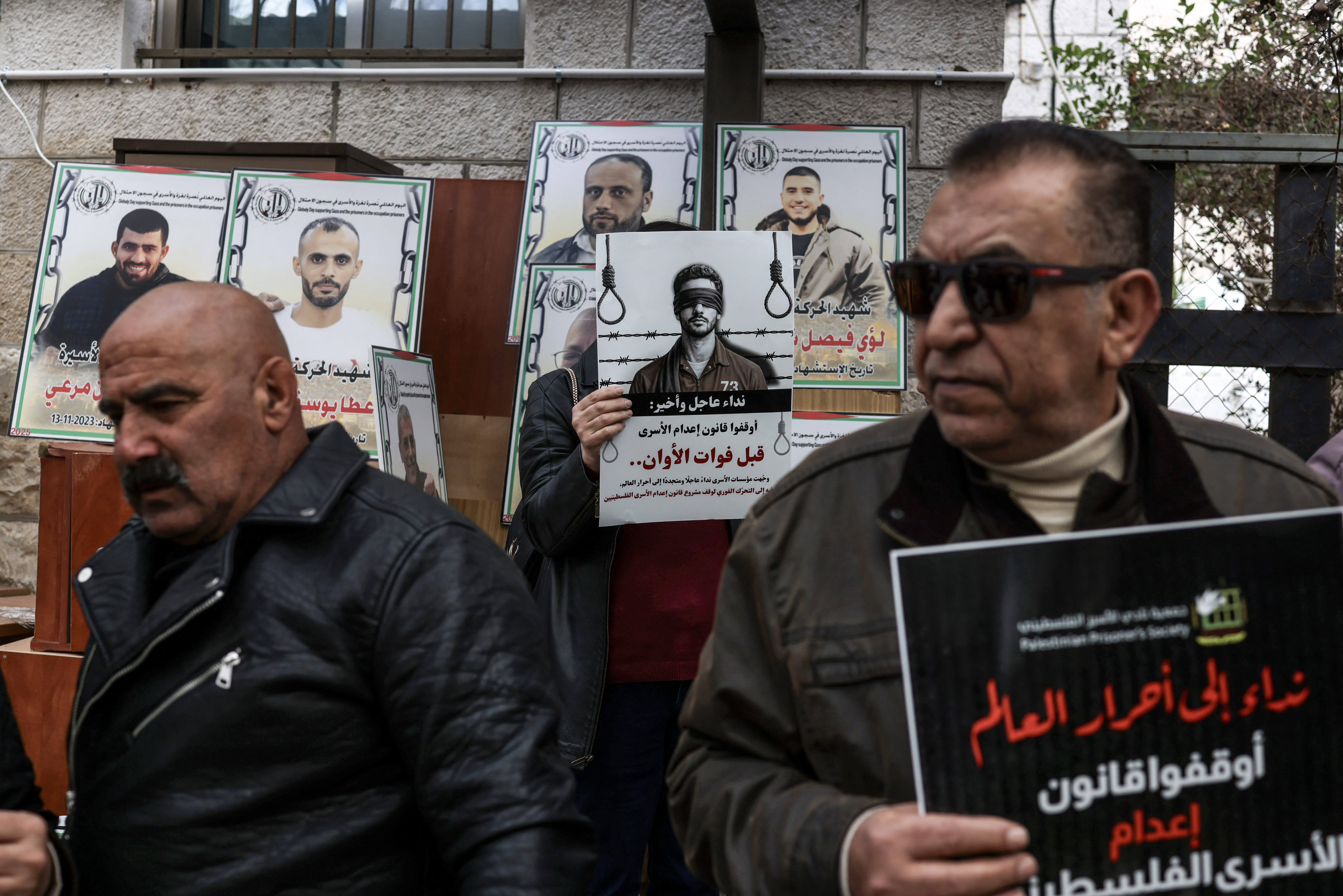 Protesters hold placards outside the Red Cross offices in Ramallah, in the Israeli-occupied West Bank, on March 31, 2026, during a rally against a bill approved by Israel's parliament that would allow the execution of Palestinians convicted on terror charges for deadly attacks.