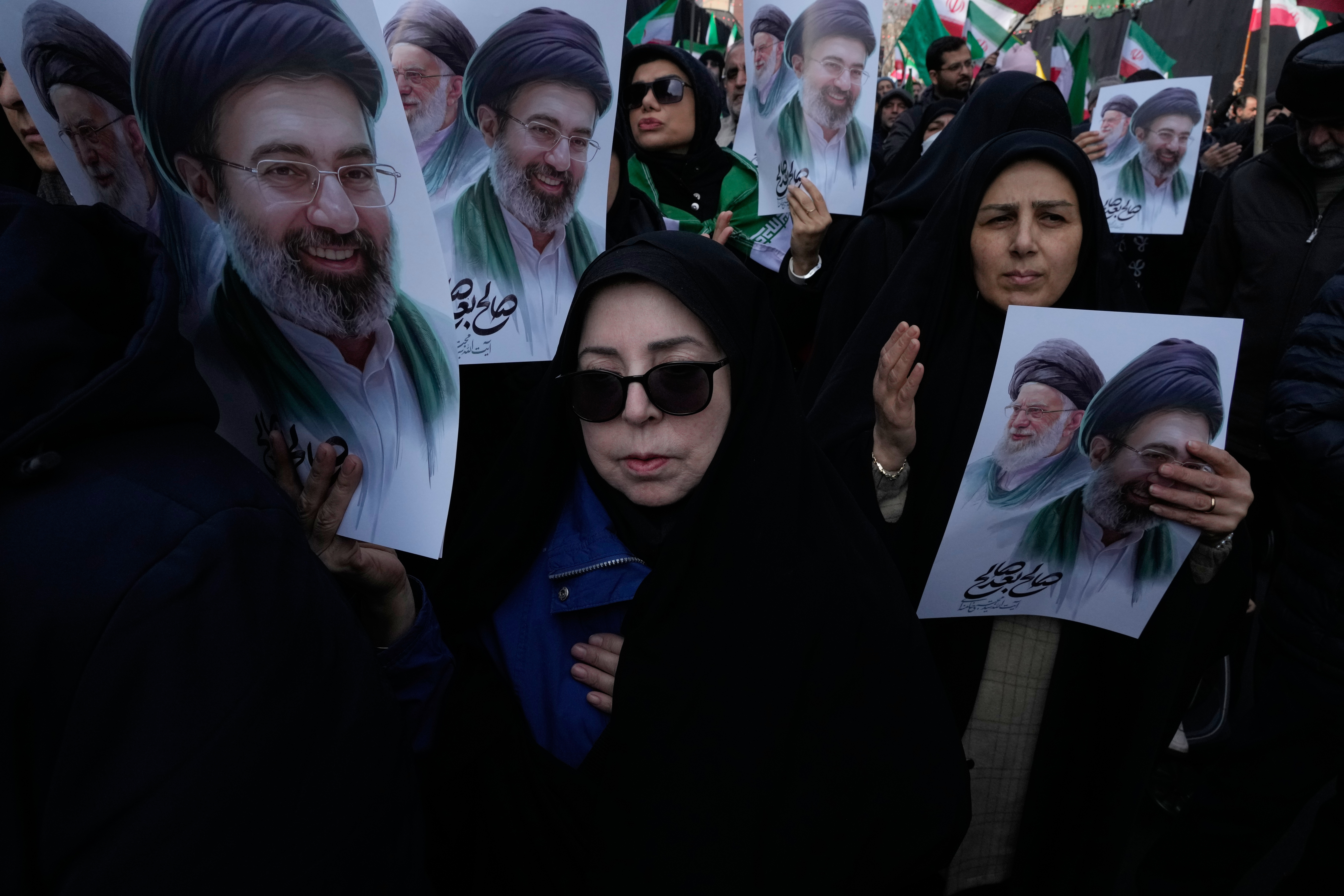 Mourners hold posters depicting Ayatollah Mojtaba Khamenei, right in the posters, the successor to his late father Ayatollah Ali Khamenei, left in the posters, as supreme leader, during the funeral procession for senior Iranian military officials and civilians killed during the U.S.-Israel campaign in Tehran, Iran, Wednesday, March 11, 2026. (AP Photo/Vahid Salemi)