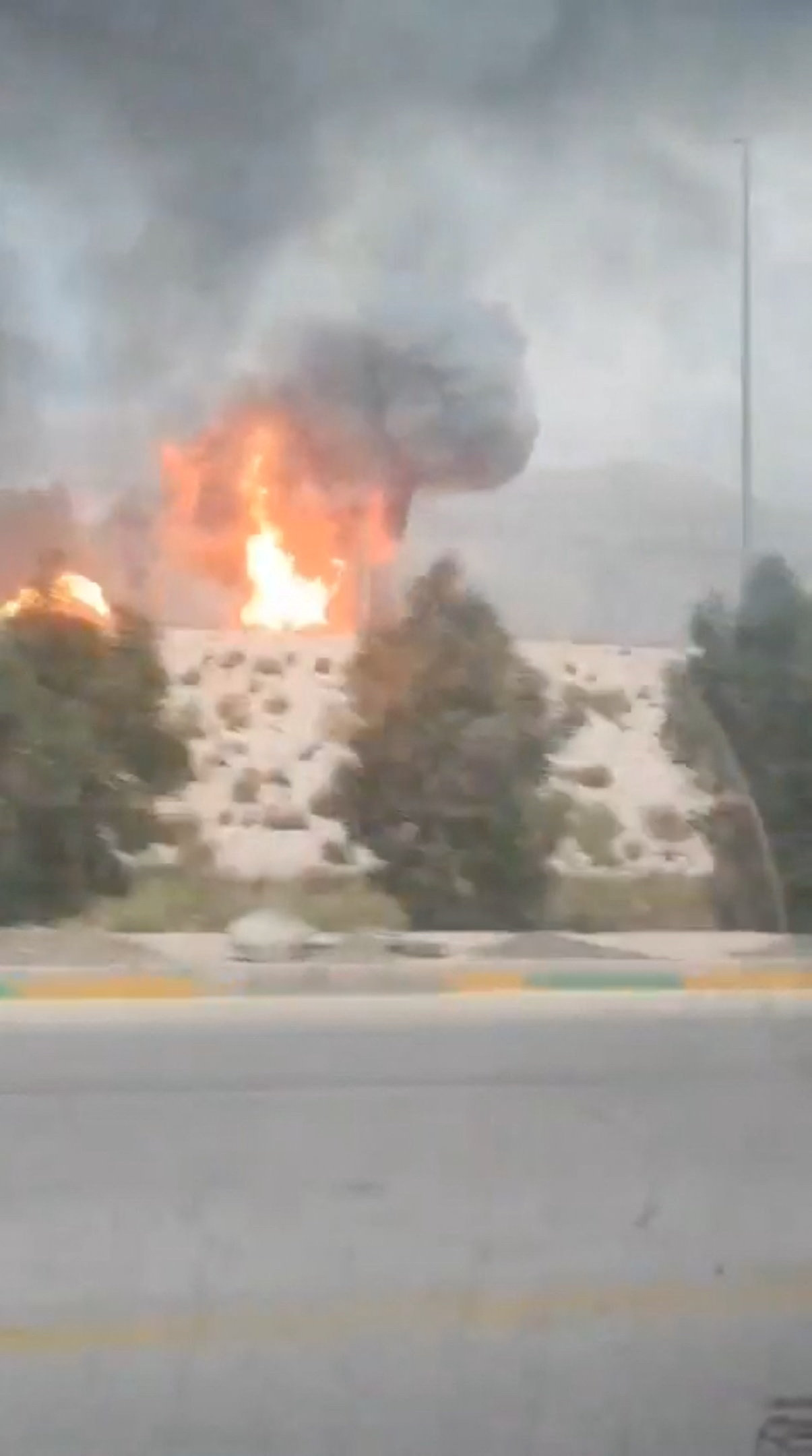 Smoke and flames rise from the South Pars gas field following an Israeli strike, as seen through the window of a moving vehicle, amid the U.S.-Israeli conflict with Iran, in Asaluyeh, Bushehr Province, Iran, March 18, 2026, in this screen grab obtained from social media video. Social Media/via REUTERS THIS IMAGE HAS BEEN SUPPLIED BY A THIRD PARTY. NO RESALES. NO ARCHIVES. VERIFICATION: - Road layout, car port, toll booths and trees matched satellite imagery. - Coordinates: 27.52556946527111, 52.568484893686 - Iranian media, Fars news agency, reported tanks and gas facilities in South Pars refinery in Asaluyeh, Iran, were hit on March 18. - No older versions of the video were found posted online before March 18.