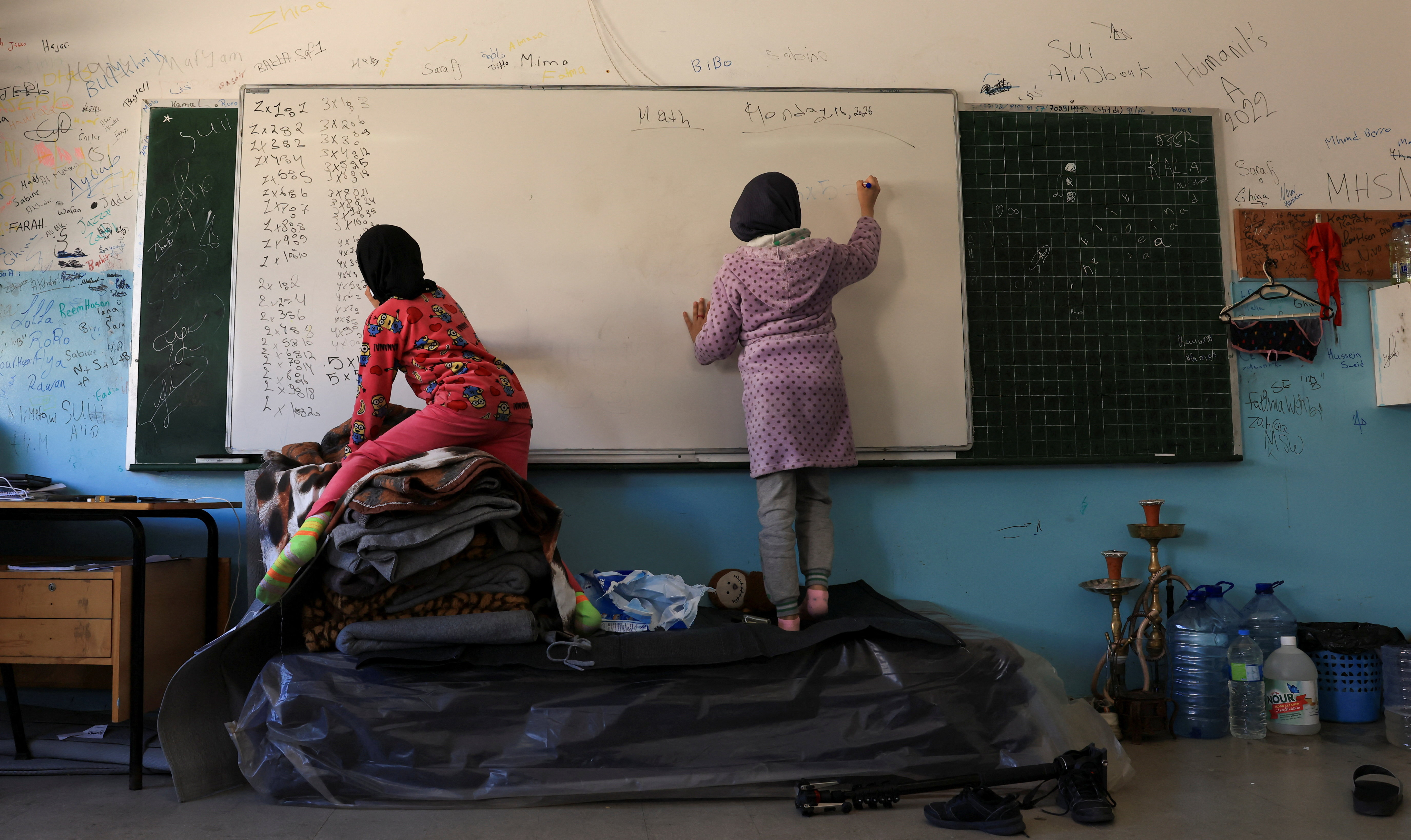 Children write on a board at a school turned into a shelter for displaced families, following an escalation between Hezbollah and Israel, amid the U.S.-Israeli conflict with Iran, in Beirut, Lebanon, March 17, 2026. [Raghed Waked/Reuters]