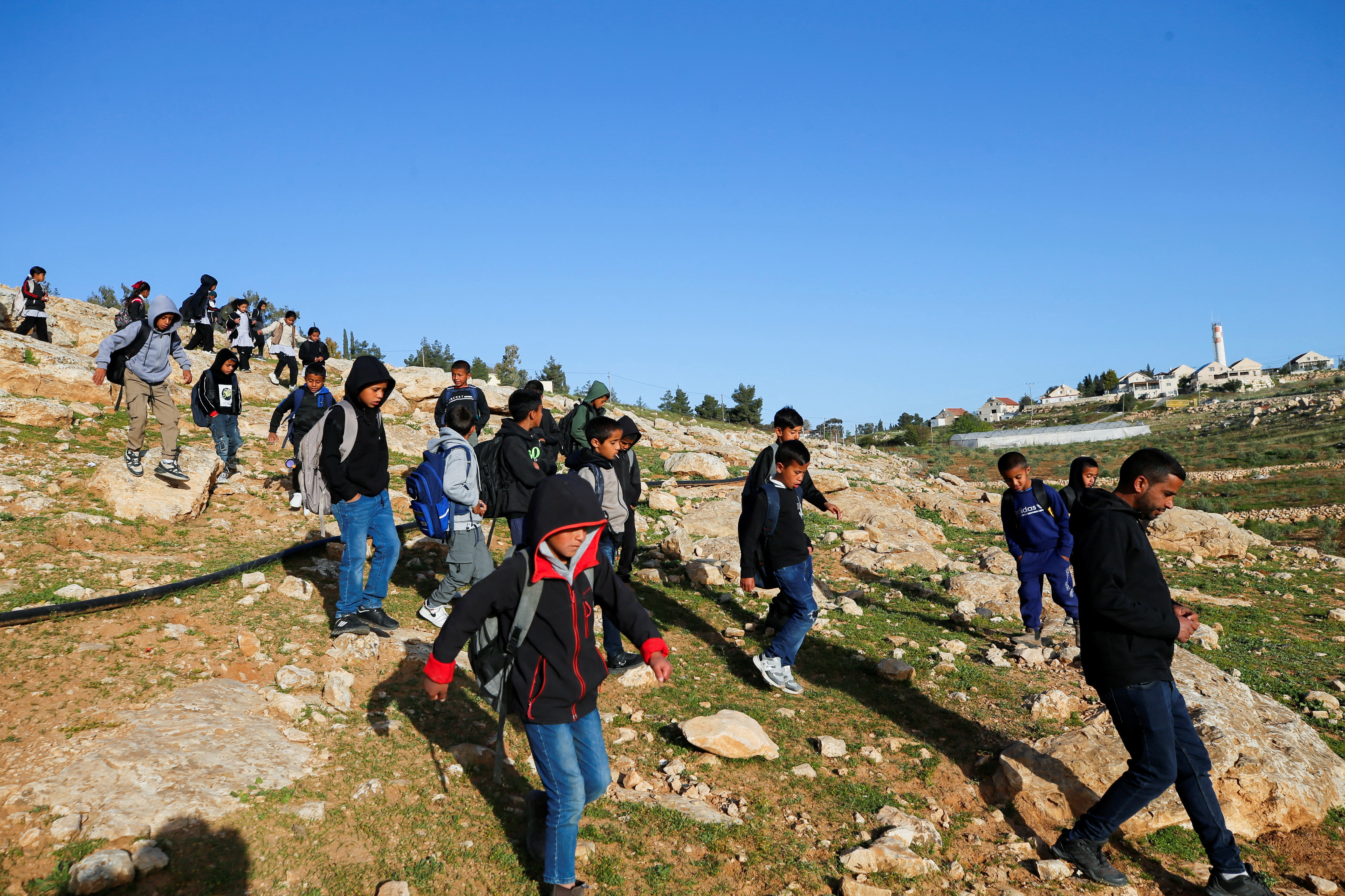 Palestinian students gather near a fence installed by Israeli settlers in their way to school, near Umm al-Khair village in Masafer Yatta, in the Israeli-occupied West Bank, April 14, 2026