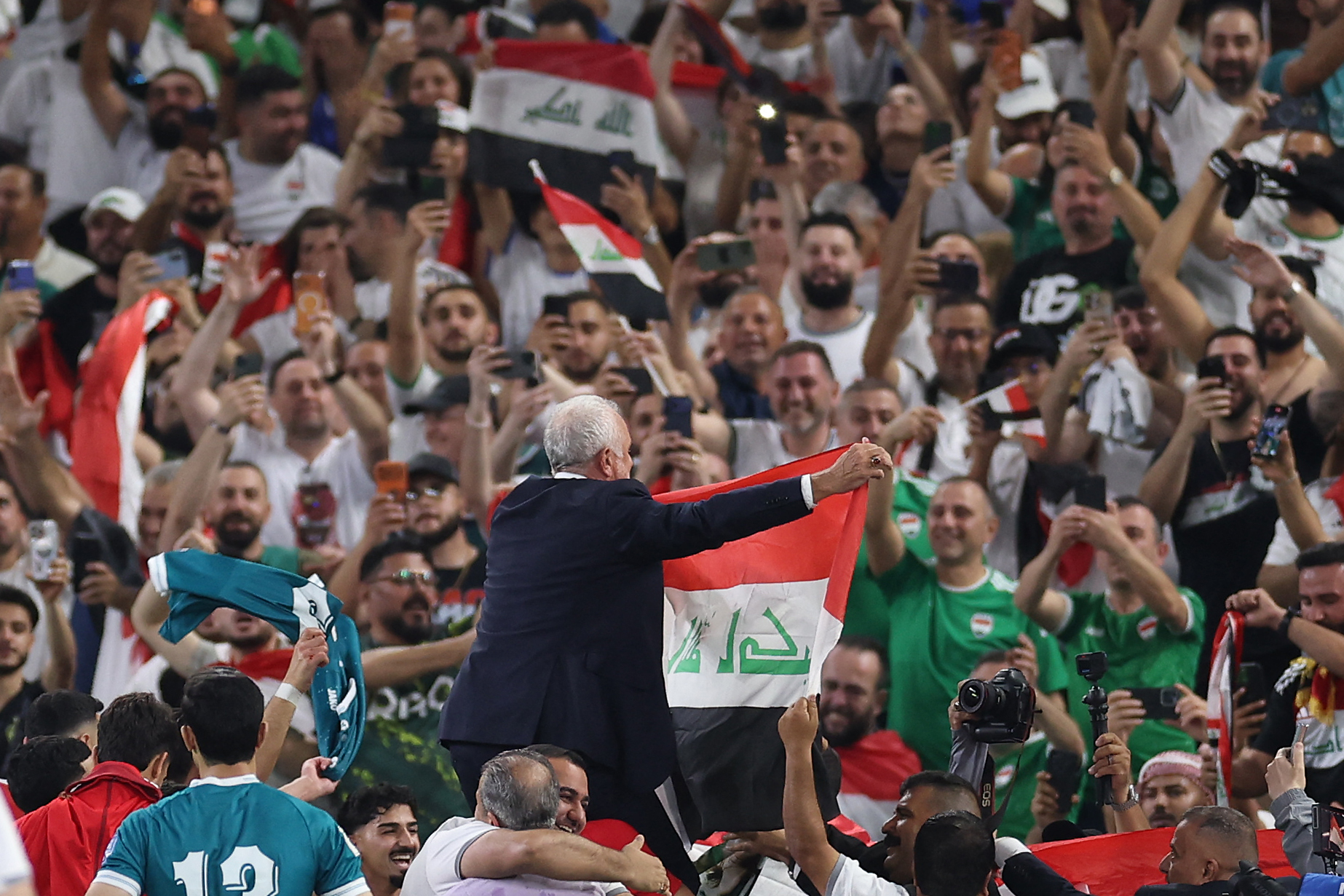 Iraq's Australian coach Graham Arnold shows the national flag to the fans after winning the 2026 FIFA World Cup qualifiers final playoff football match between Iraq and Bolivia at the BBVA Stadium in Guadalupe, Nuevo Leon state, Mexico, on March 31, 2026. (Photo by Julio Cesar AGUILAR / AFP)