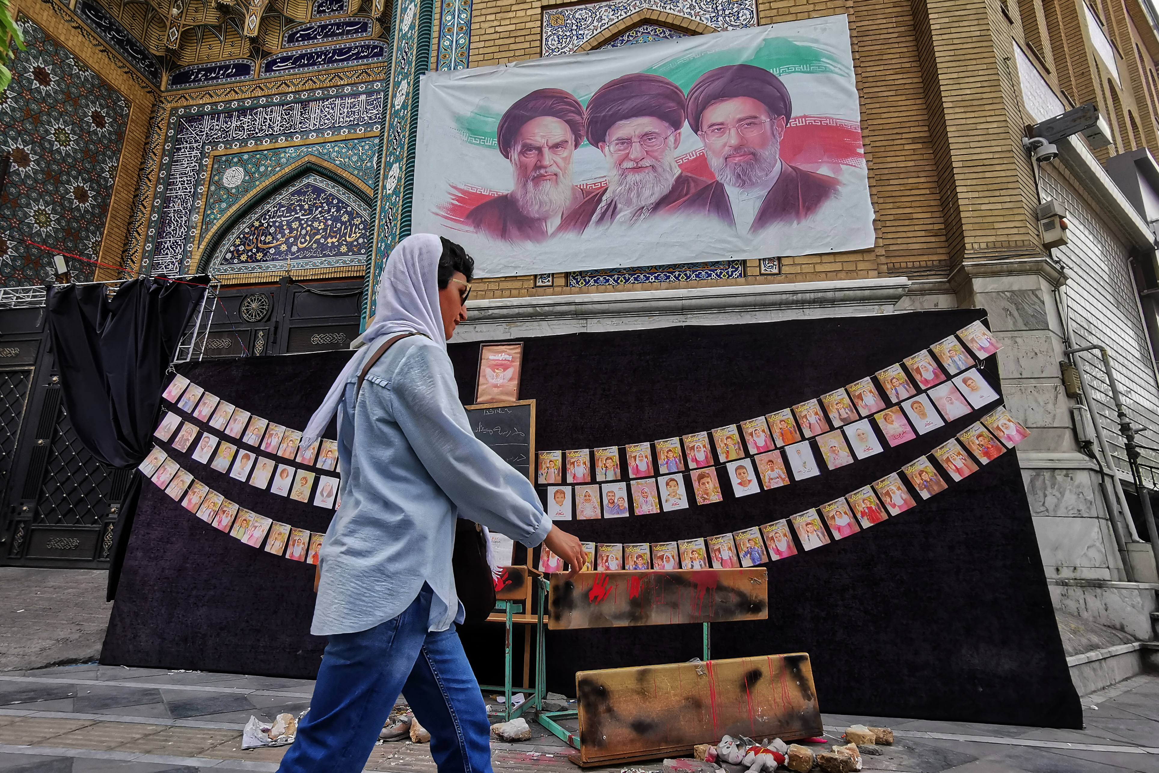 A woman walks past images of Iran's former supreme leaders, Ayatollah Ruhollah Khomeini and Ayatollah Ali Khamenei, next to the incumbent, Mojtaba Khamenei, in Tehran