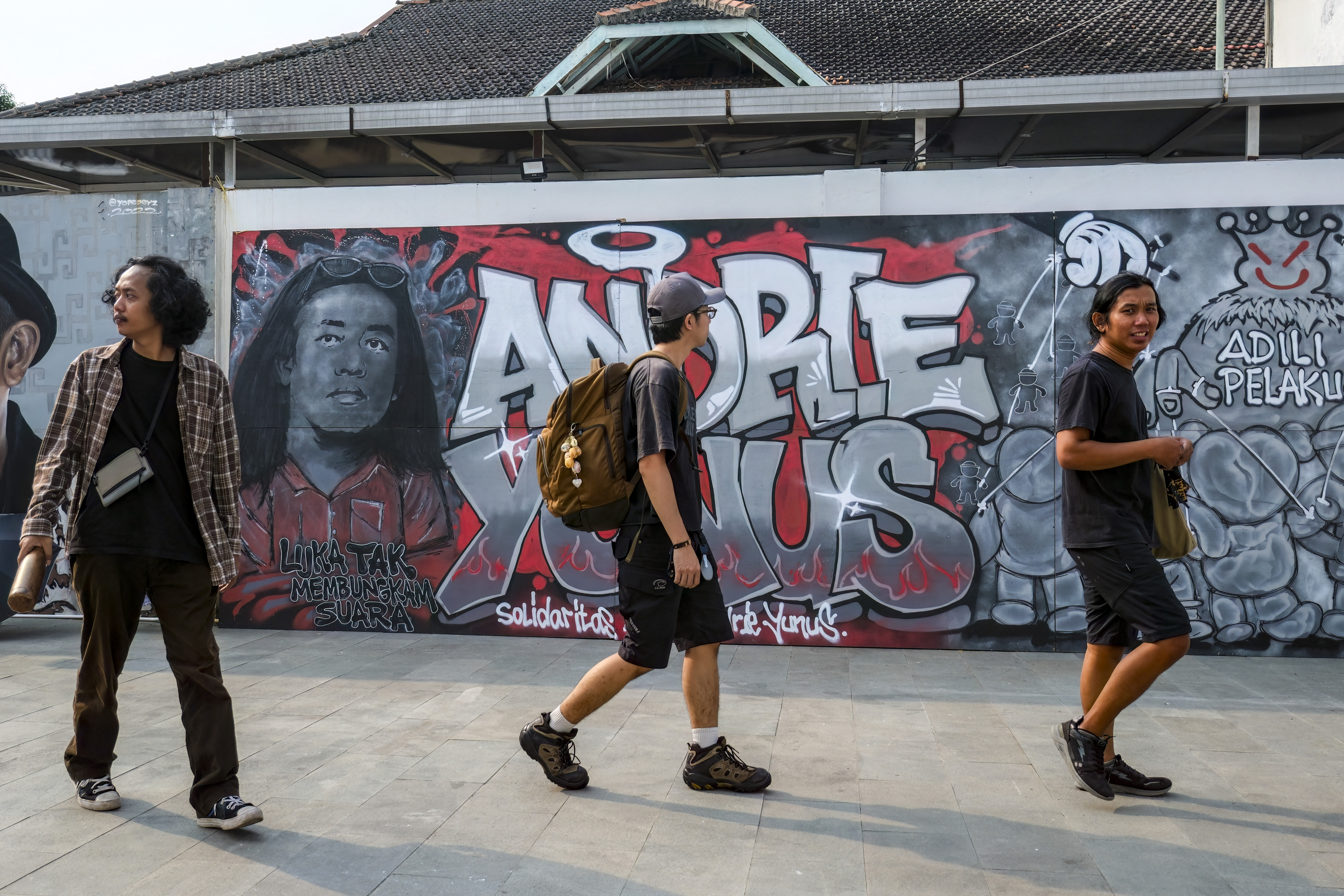 Visitors walk past a mural featuring Andrie Yunus, the deputy coordinator of the KontraS rights group who suffered serious injuries when two men on a scooter threw acid at him, at a Mural Exhibition, "From Citizens for Andrie", in Jakarta, on April 27, 2026.
