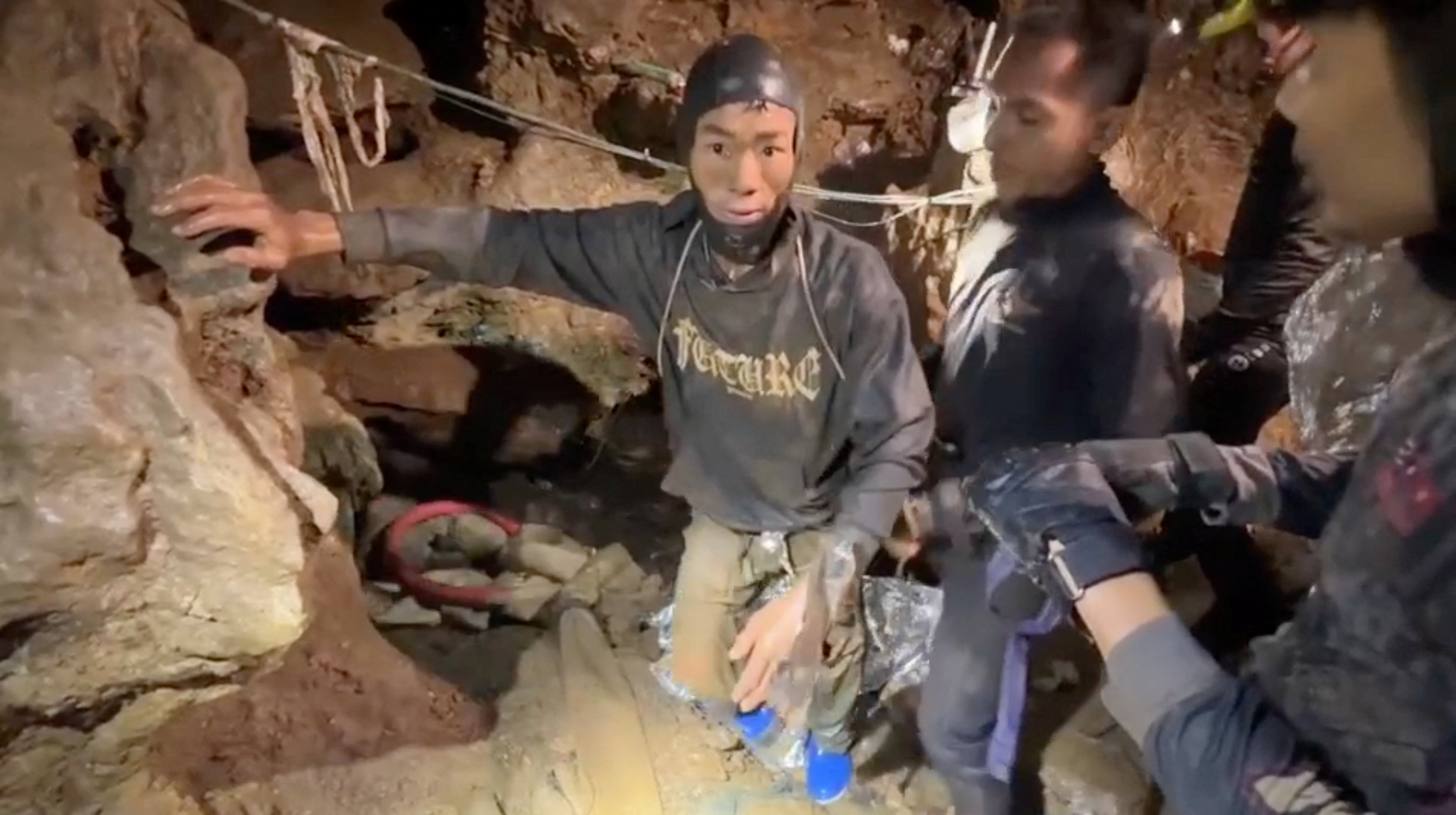 Rescuers pull out a trapped person from a flooded cave.