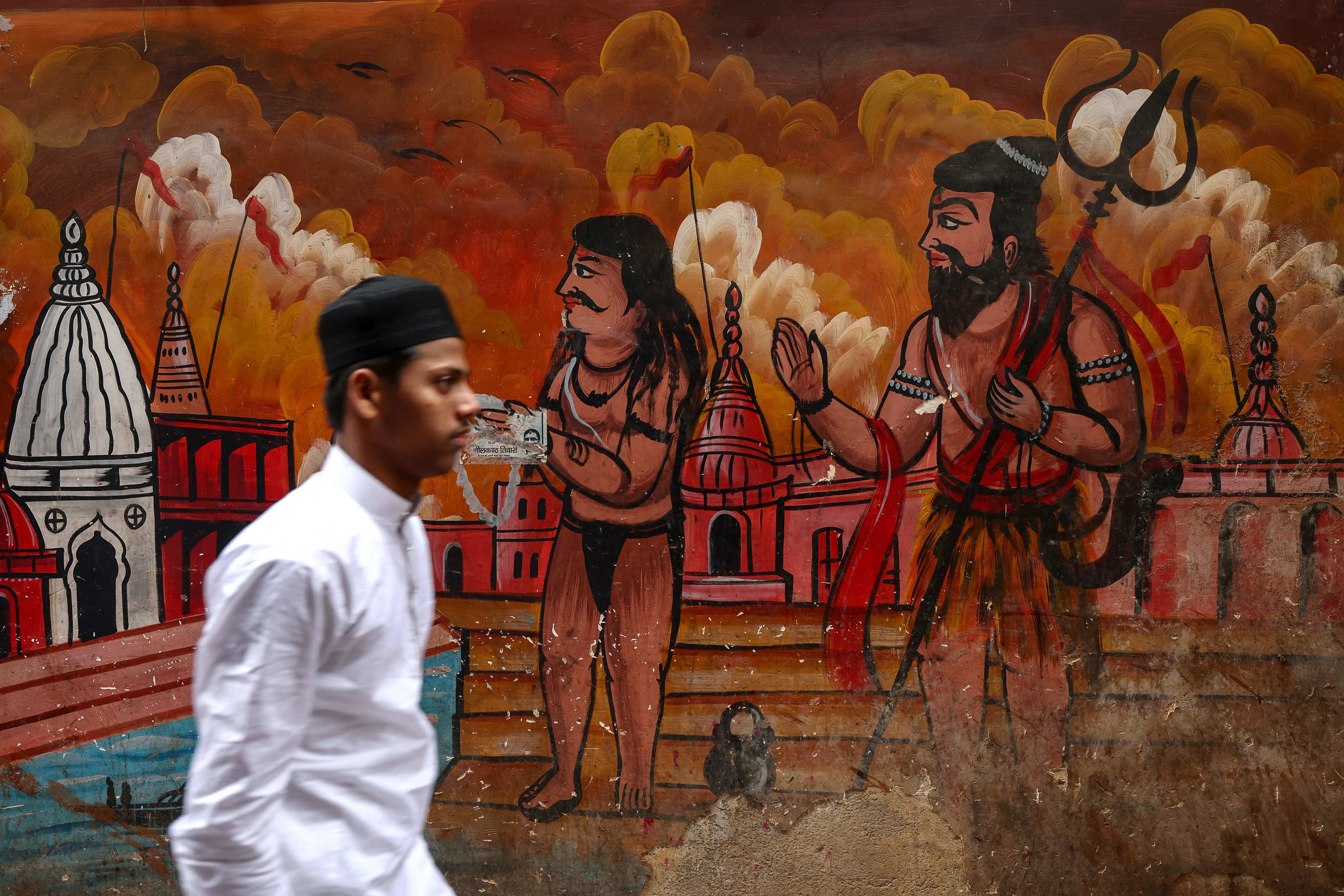 A Muslim devotee walks past a mural as he leaves after offering Eid al-Fitr prayers, which marks the end of the Islamic holy fasting month of Ramadan, at Alamgir Mosque along the banks of the river Ganges in Varanasi on March 21, 2026. [Niharika Kulkarni / AFP]