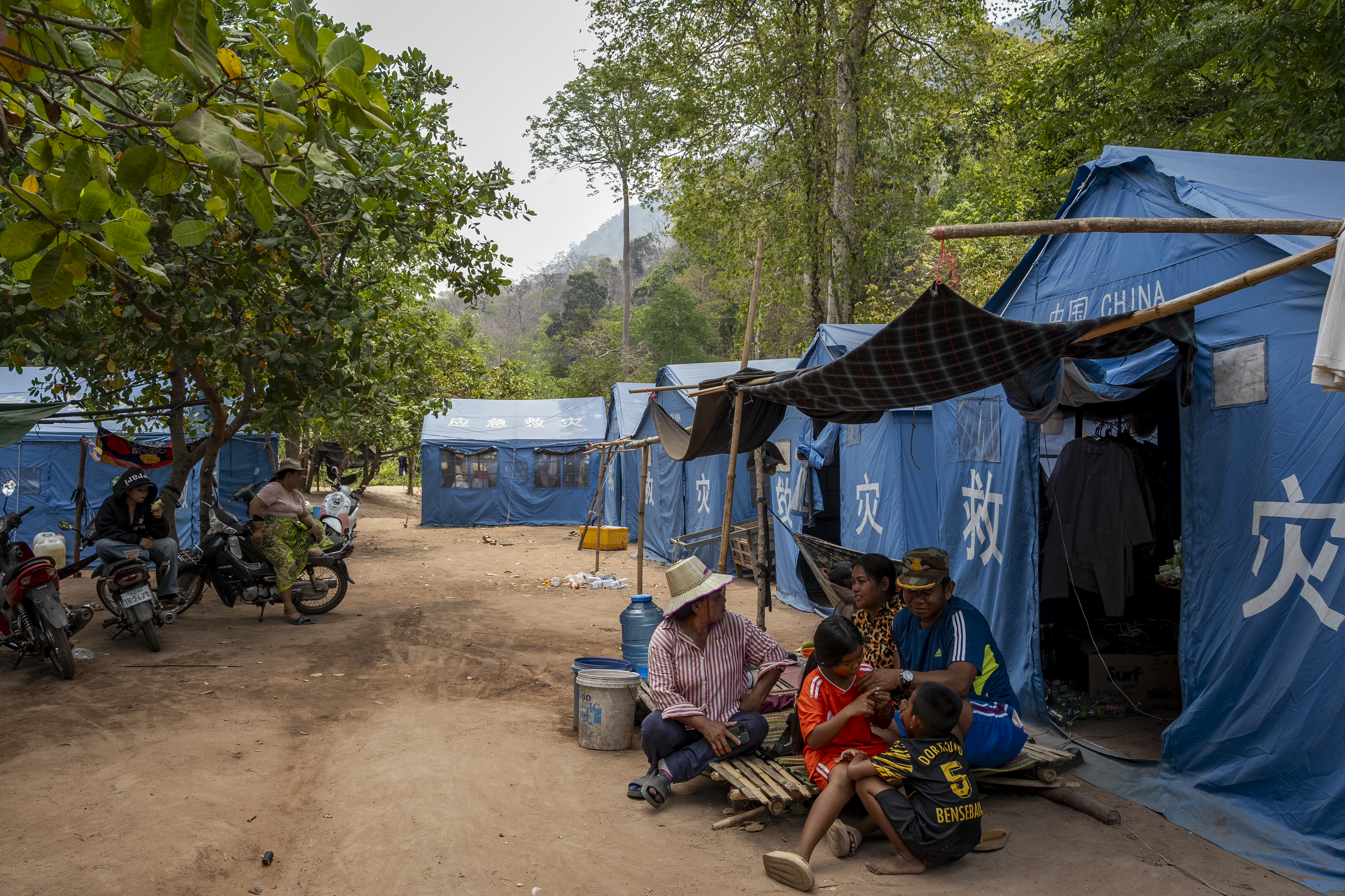 Families living temporarily at the Wat Bak Kam internal displacement camp sit outside their tents, supplied by Chinese government aid