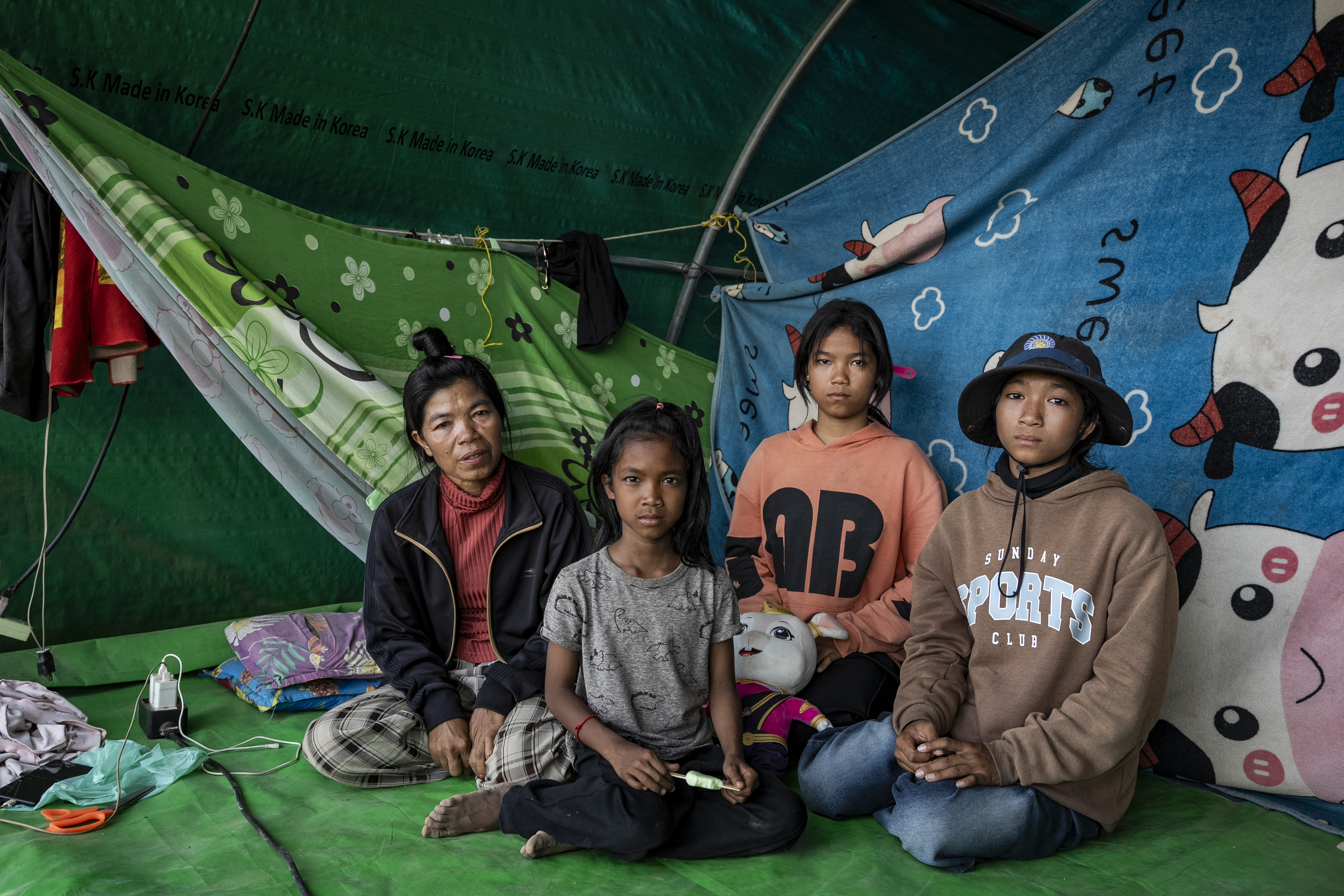 Puth Reen, left, and her three daughters sit inside their tent in a camp for the displaced at Wat Chroy Neang Ngourn in Siem Reap province