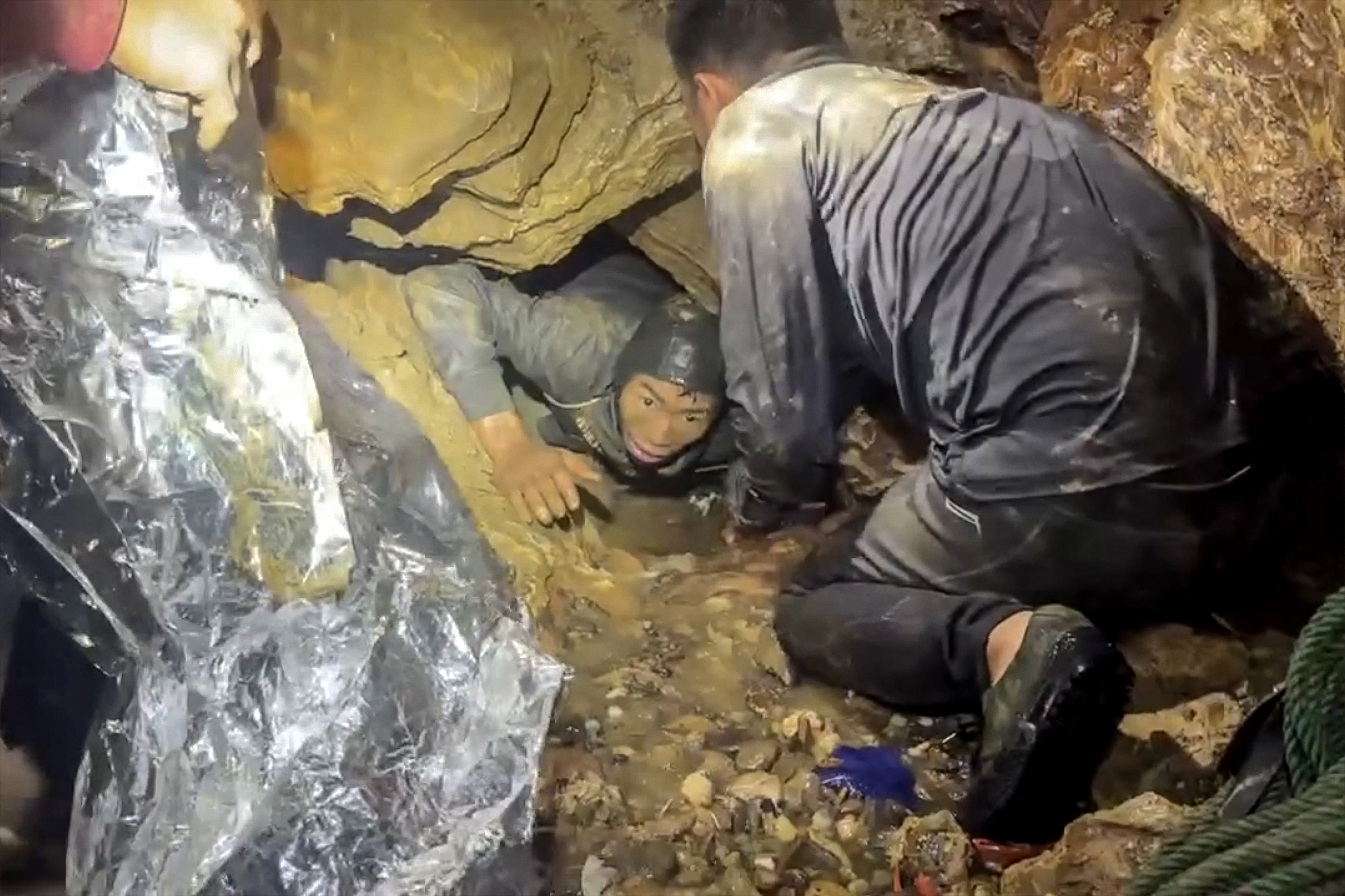 This screengrab made from handout video footage taken on May 29, 2026, and provided by Metta Tham Rescue Kalasin, shows a rescue team freeing one of seven men (L) trapped inside a semi-submerged cave in central Xaysomboun province, northeast of the capital Vientiane.