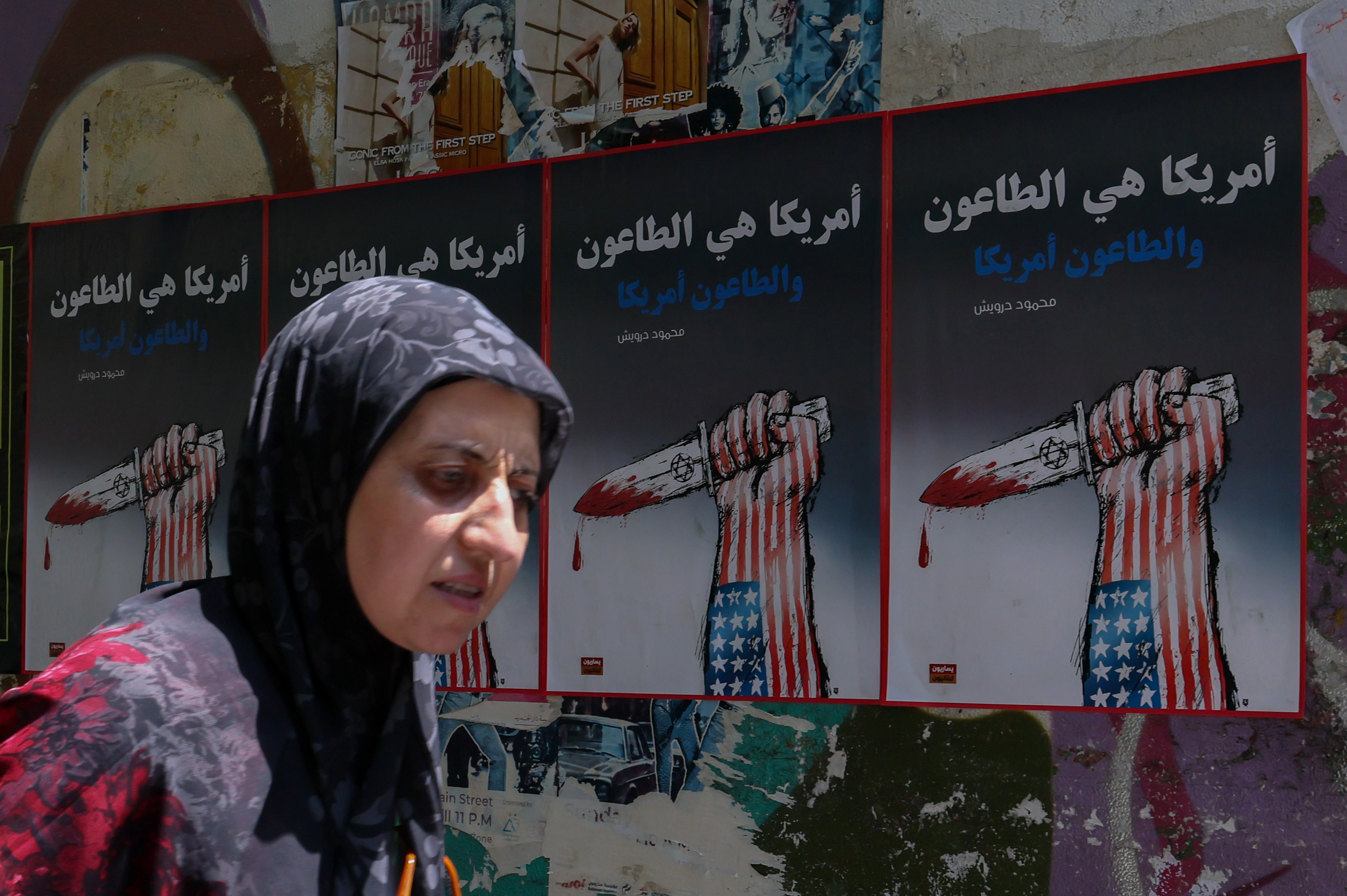 epa13026465 A woman passes by wall-mounted political posters on a street in Beirut, Lebanon, 09 June 2026. The posters depict a hand decorated in the colors of the US flag holding a dagger that symbolizes Israel and reading 'America is a plague, and the plague is America'. The Lebanese Ministry of Health said that, as of 08 June, Israeli attacks across Lebanon have killed more than 3,637 people and injured more than 11,188 since renewed hostilities between Israel and Hezbollah began. EPA/WAEL HAMZEH
