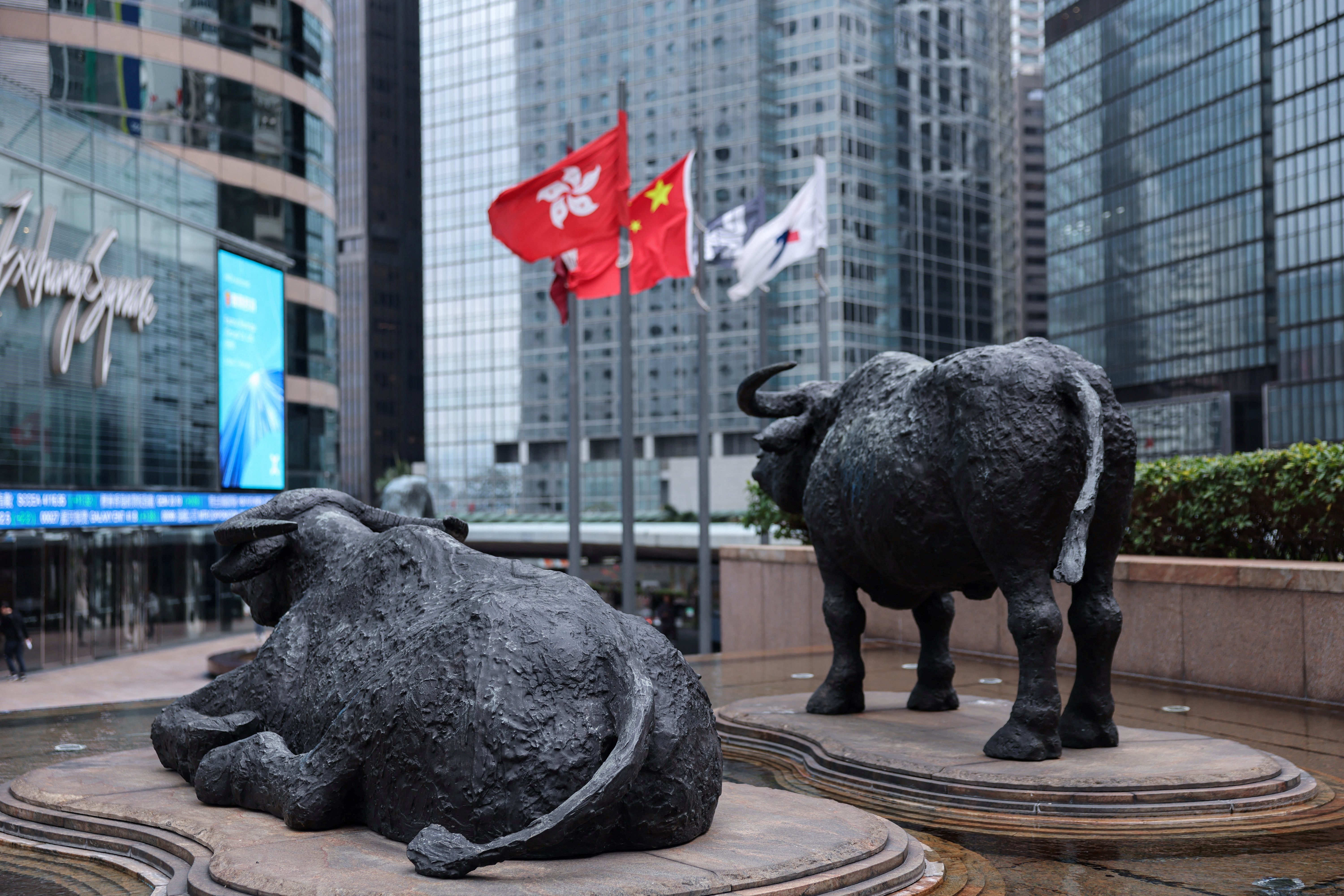 Bull statues stand near screens showing the Hang Seng stock index, outside Exchange Square, in Hong Kong, China, on February 3, 2026