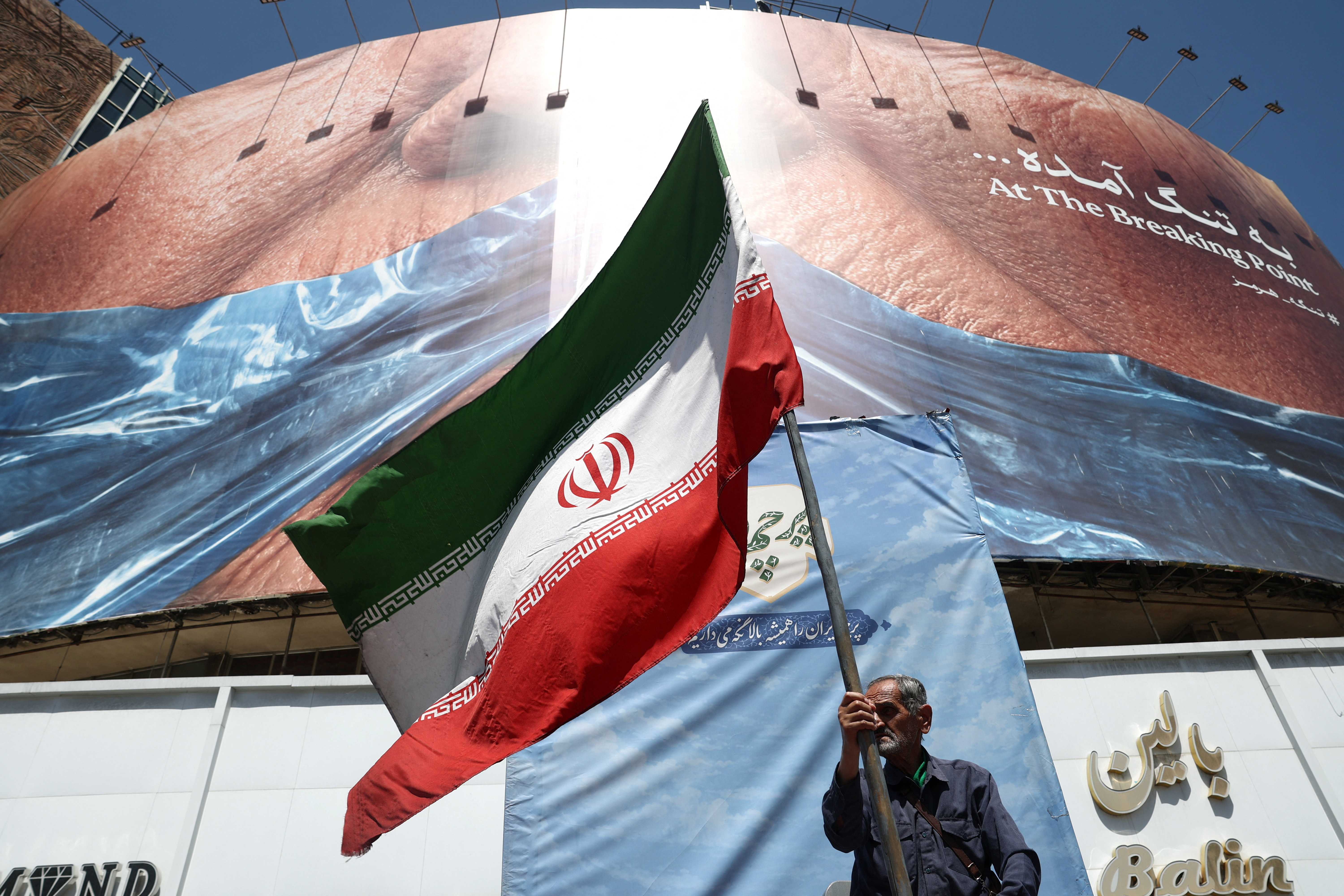 A man holds an Iranian flag near an anti-U.S. billboard depicting U.S. President Donald Trump and the Strait of Hormuz, in Tehran, Iran, May 30, 2026. Majid Asgaripour/WANA (West Asia News Agency) via REUTERS ATTENTION EDITORS - THIS PICTURE WAS PROVIDED BY A THIRD PARTY. ISRAEL OUT. NO COMMERCIAL OR EDITORIAL SALES IN ISRAEL. NO ACCESS FOR ISRAELI MEDIA. NO USE BBC PERSIAN. NO USE VOA PERSIAN. NO USE MANOTO. NO USE IRAN INTERNATIONAL. NO USE RADIO FARDA. DIGITAL: NO USE BBC PERSIAN. NO USE VOA PERSIAN. NO USE MANOTO. NO USE IRAN INTERNATIONAL. NO USE RADIO FARDA.