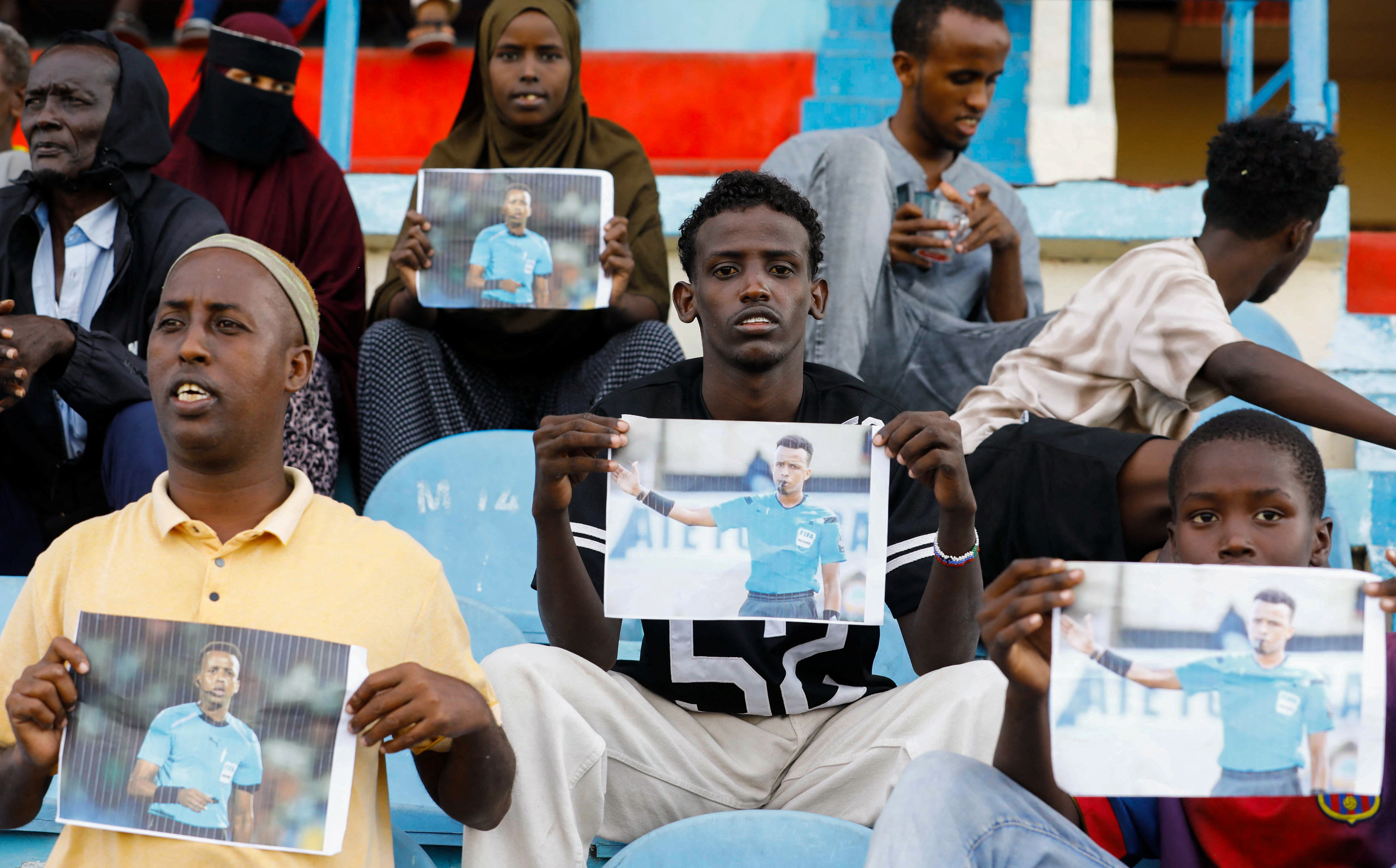 Somalis hold pictures of referee Omar Abdulkadir Artan, who had been expected to officiate matches at the 2026 FIFA World Cup but was refused entry to the United States, during a match between Gaadiidka and Juba at Mogadishu Stadium, in Mogadishu, Somalia, June 9, 2026. REUTERS/Feisal Omar
