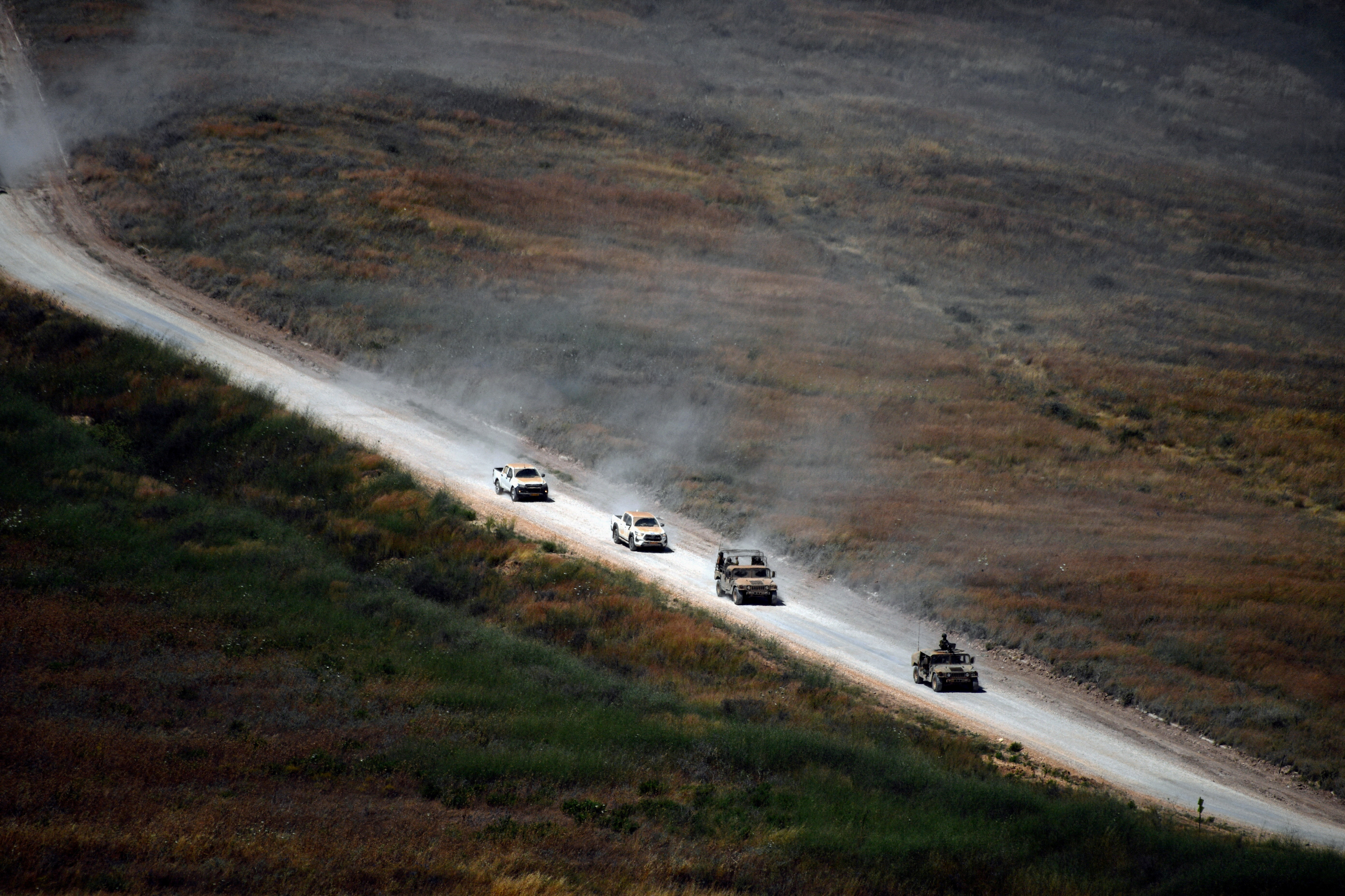 Israeli military vehicles drive on a Lebanese road by the Israel-Lebanon border, as seen from northern Israel, June 18, 2026